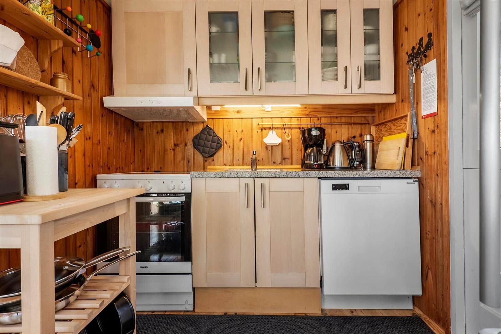 Kitchen with wooden walls, white appliances, and wooden cabinets. Countertop, sink, and stove are visible.