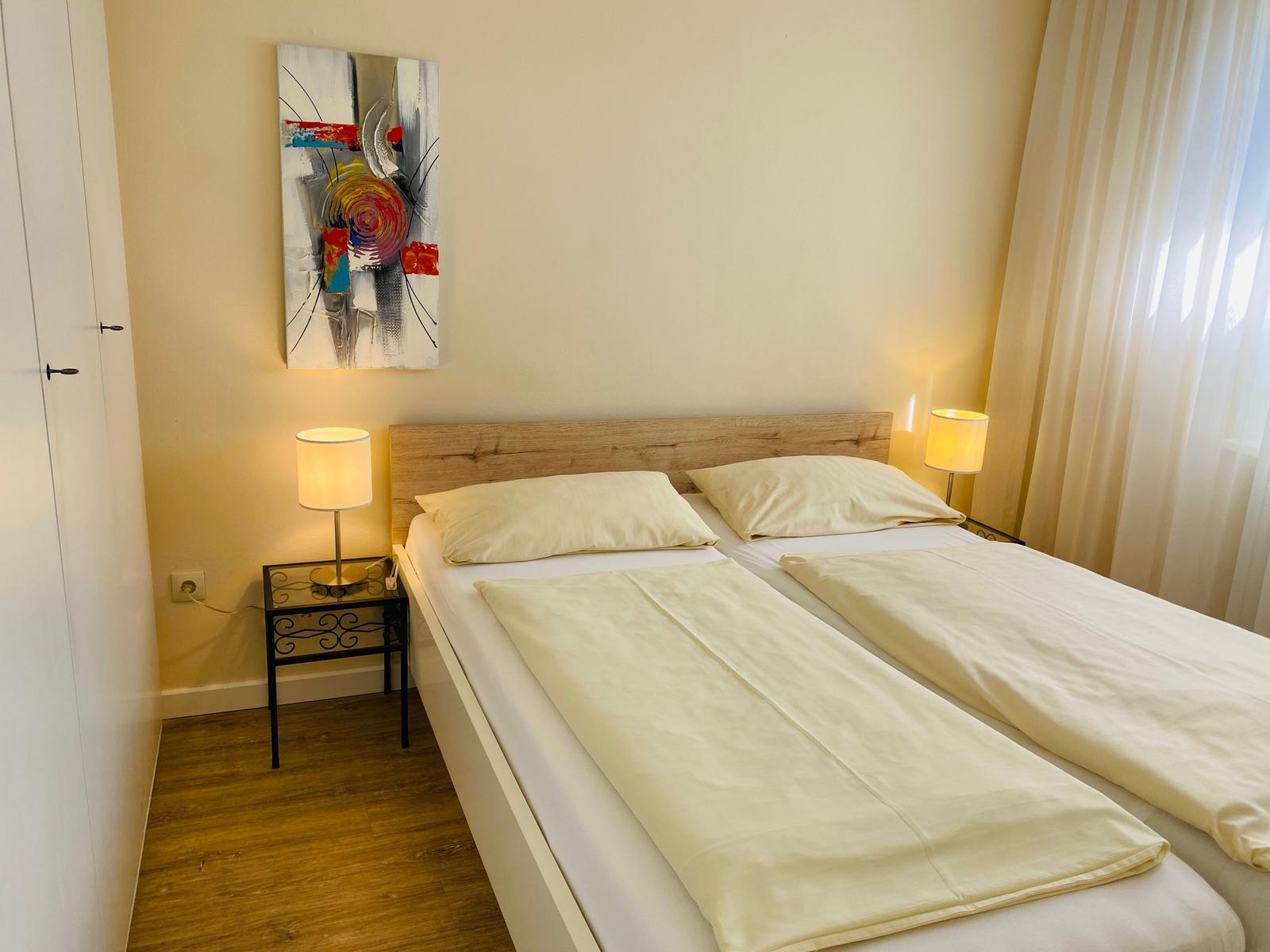 Schlafzimmer mit Doppelbett, Nachttischen und Wandbild.