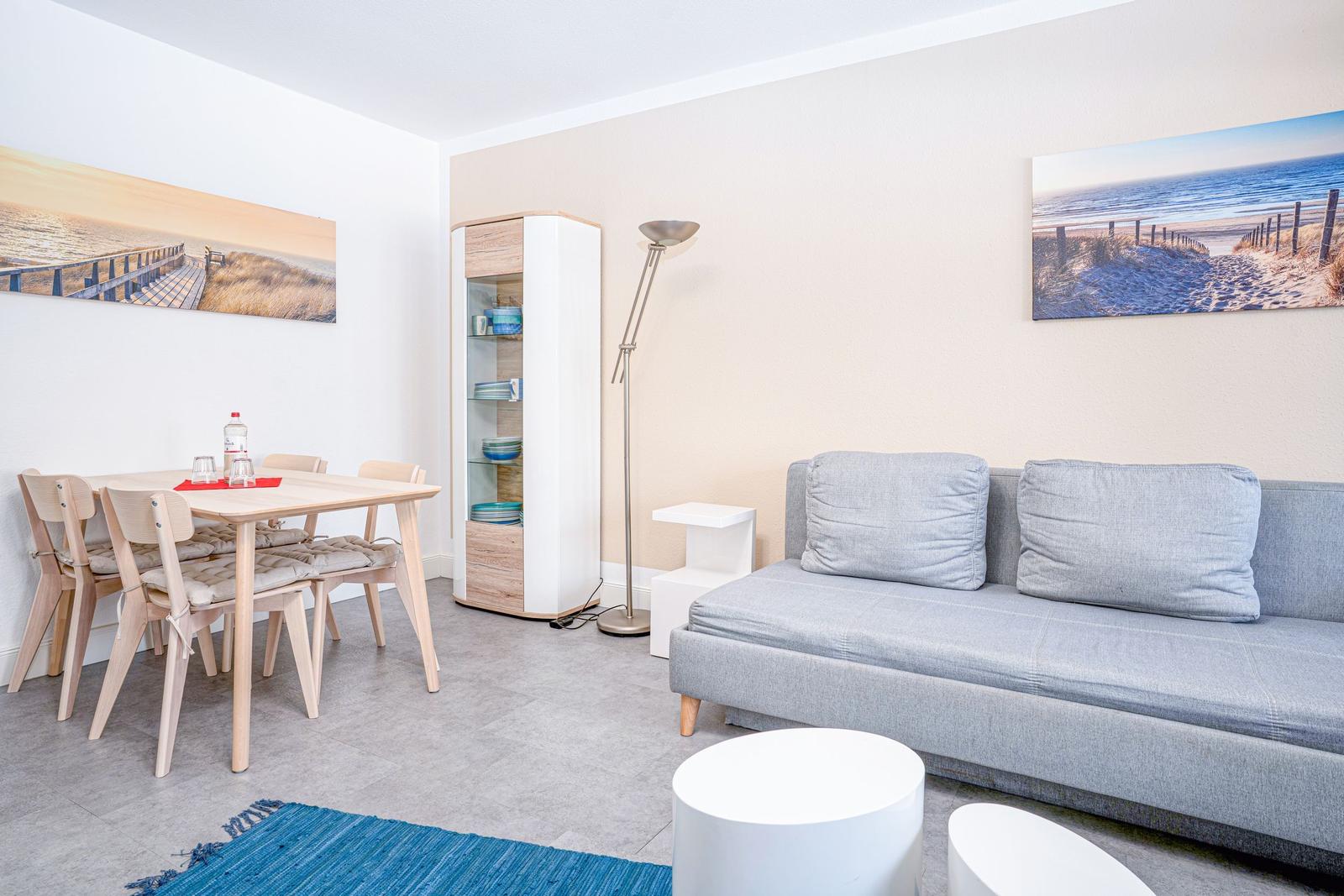 Wohn- und Essbereich mit Sofa, Tisch, Stühlen und Wandbildern