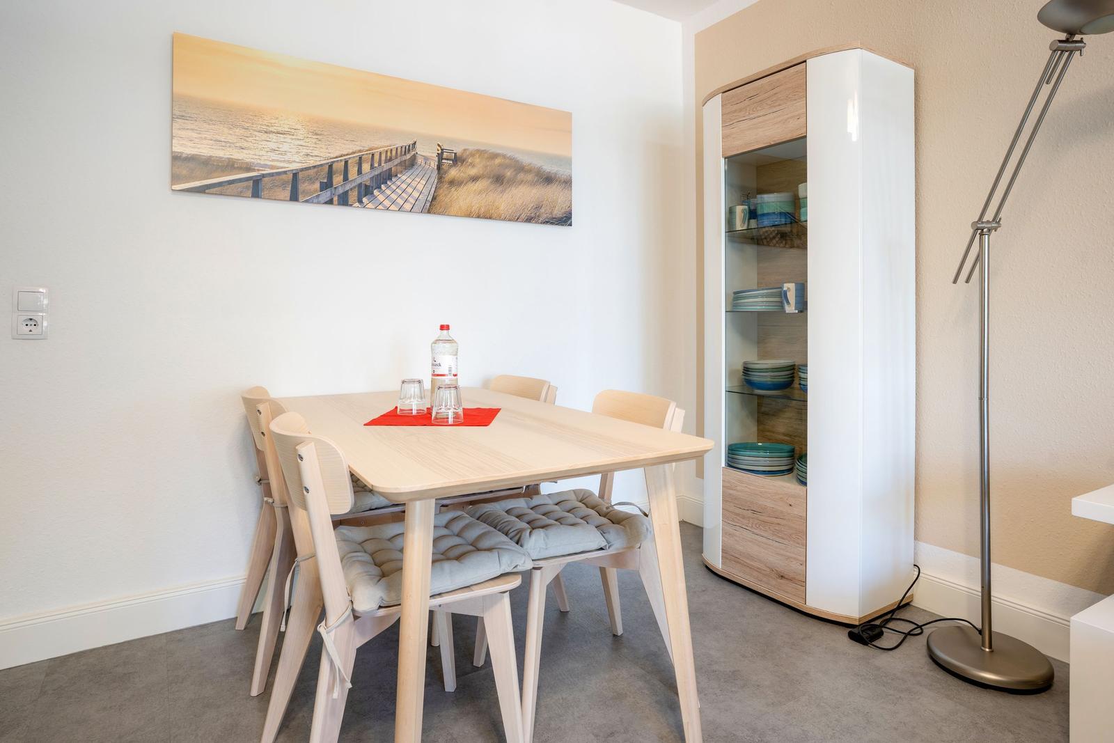 Esstisch mit vier Stühlen, Küchenschrank und Wandbild an der Wand.