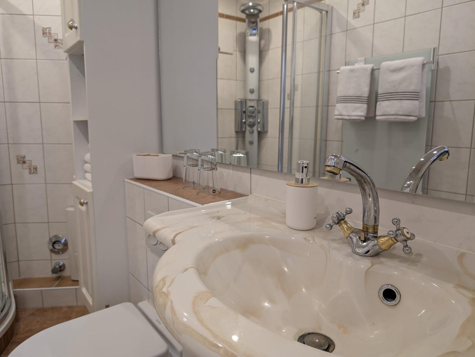 Badezimmer mit Waschbecken, Spiegel und Dusche