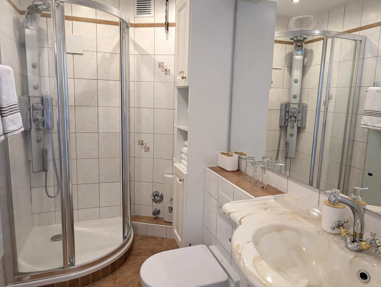 Badezimmer mit Dusche, Waschbecken und Toilette.