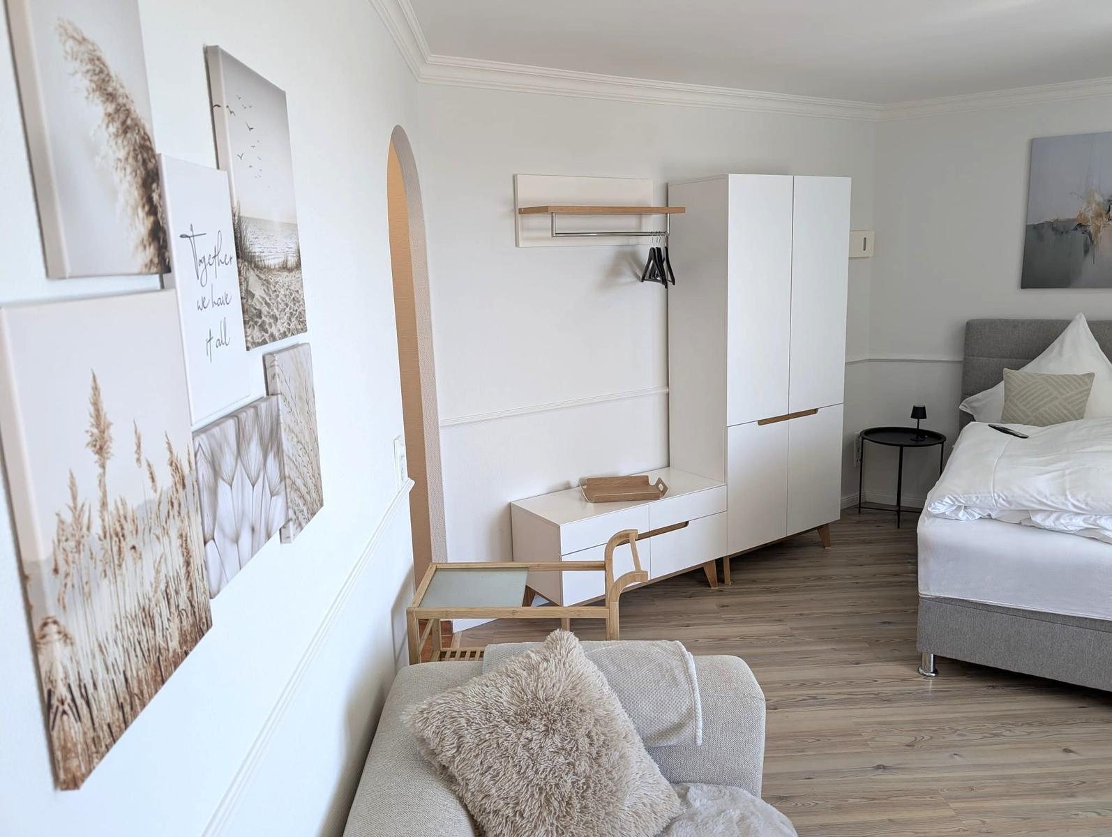 Schlafzimmer mit Bett, Kleiderschrank und Wandbildern