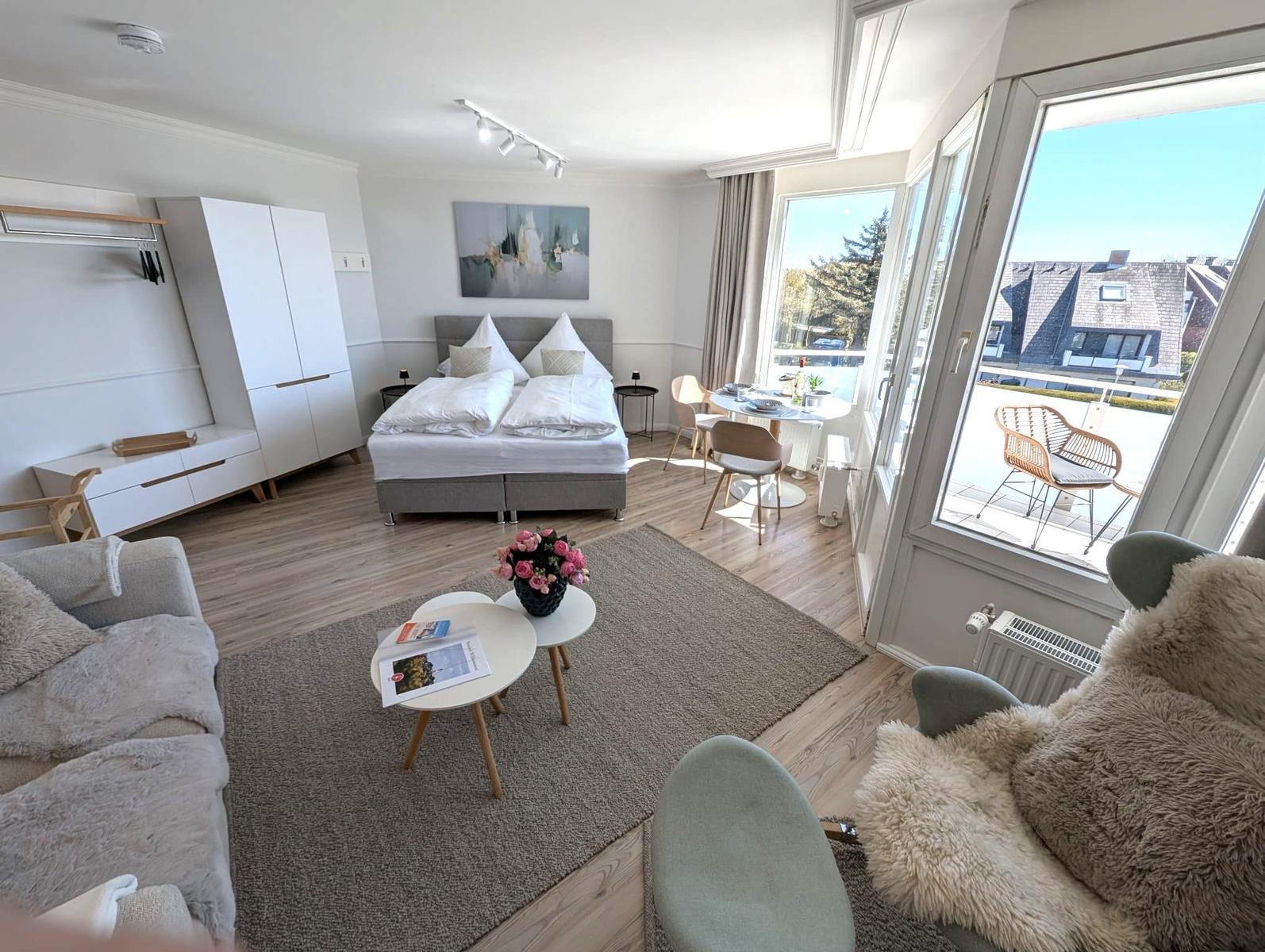 Ein Schlafzimmer mit Bett, Sofa, Tisch und Balkon.