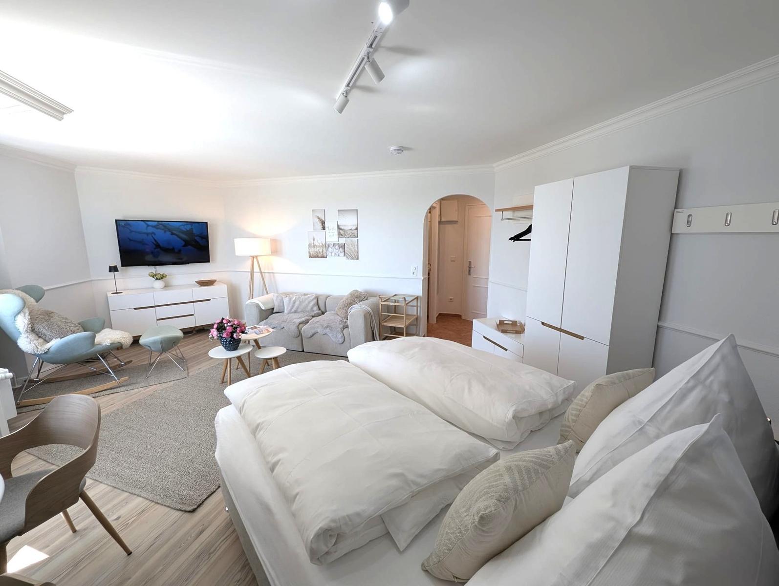 Schlafzimmer mit Doppelbett, Sofa, Fernseher und Kleiderschrank.