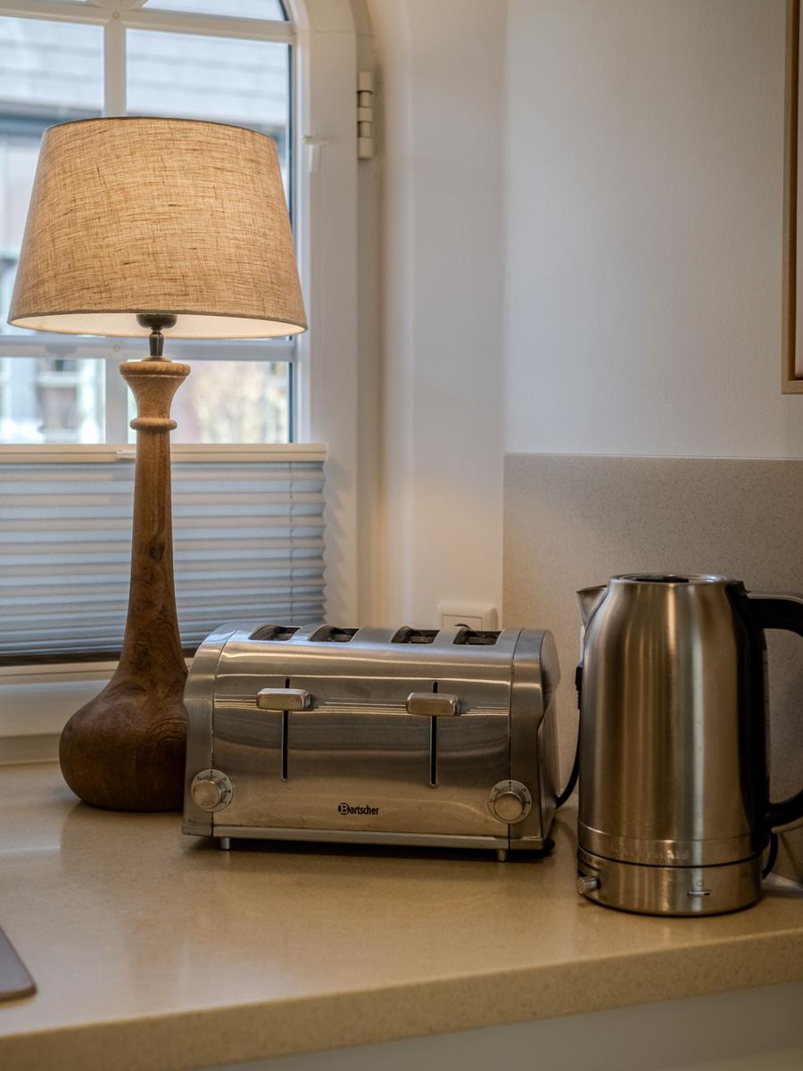 Küchenarbeitsfläche mit Toaster, Kaffeekocher und Stehlampe vor Fenster