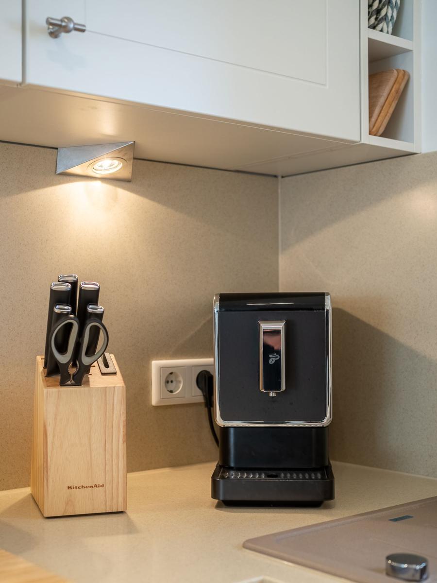 Küchenzeile mit Messerblock und Kaffeemaschine unter Schrank.