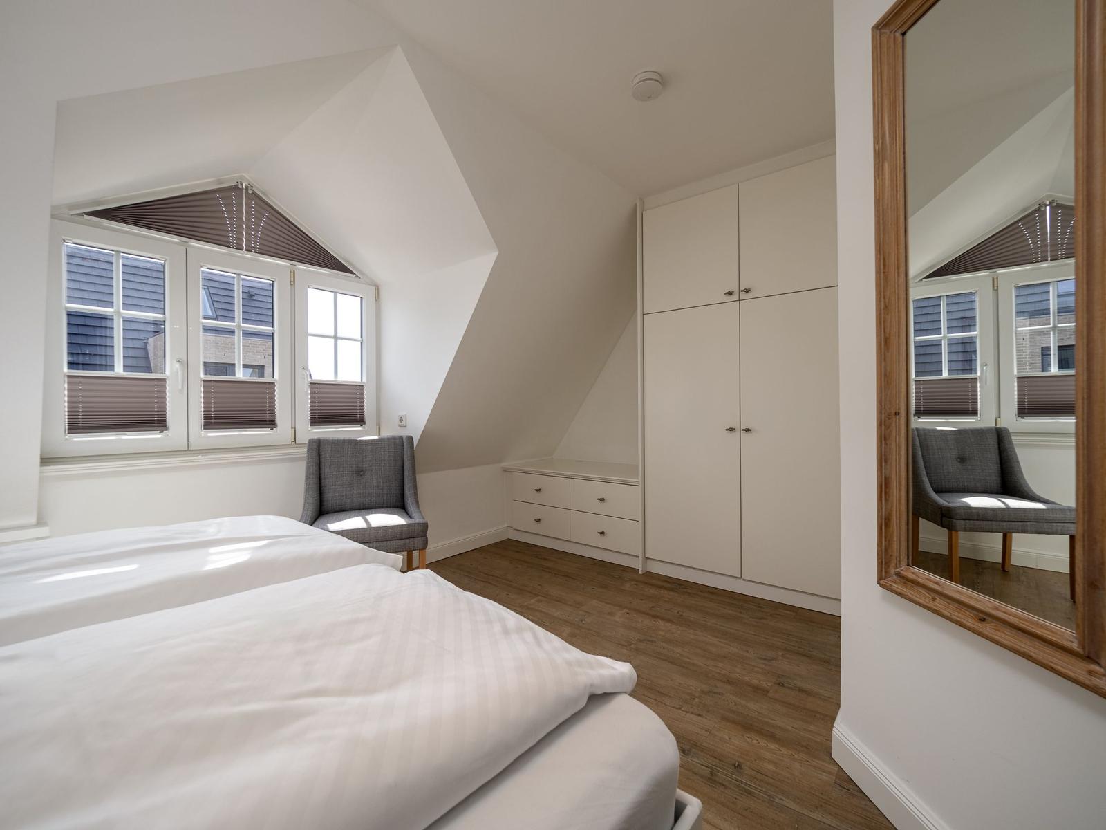 Schlafzimmer mit Dachschrägen, Bett, Kleiderschrank und Spiegel