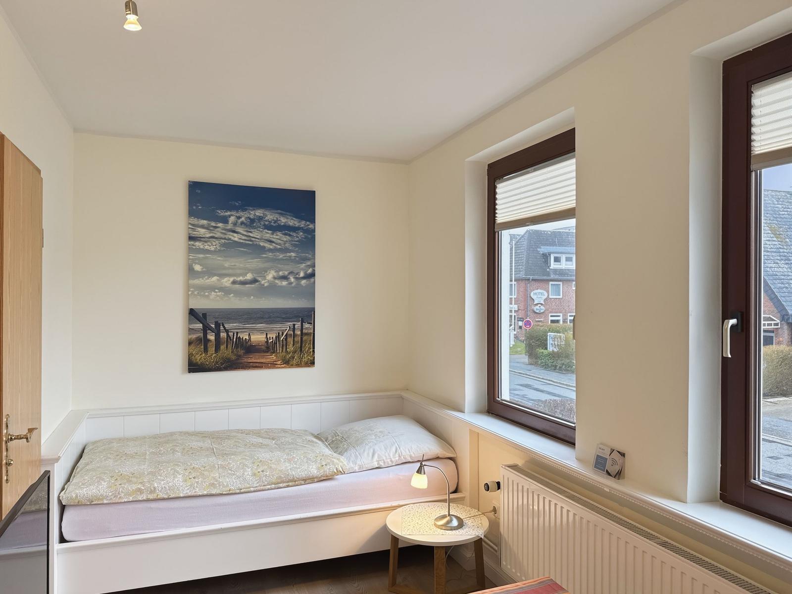 Bedroom with bed, wall art, and window view.
