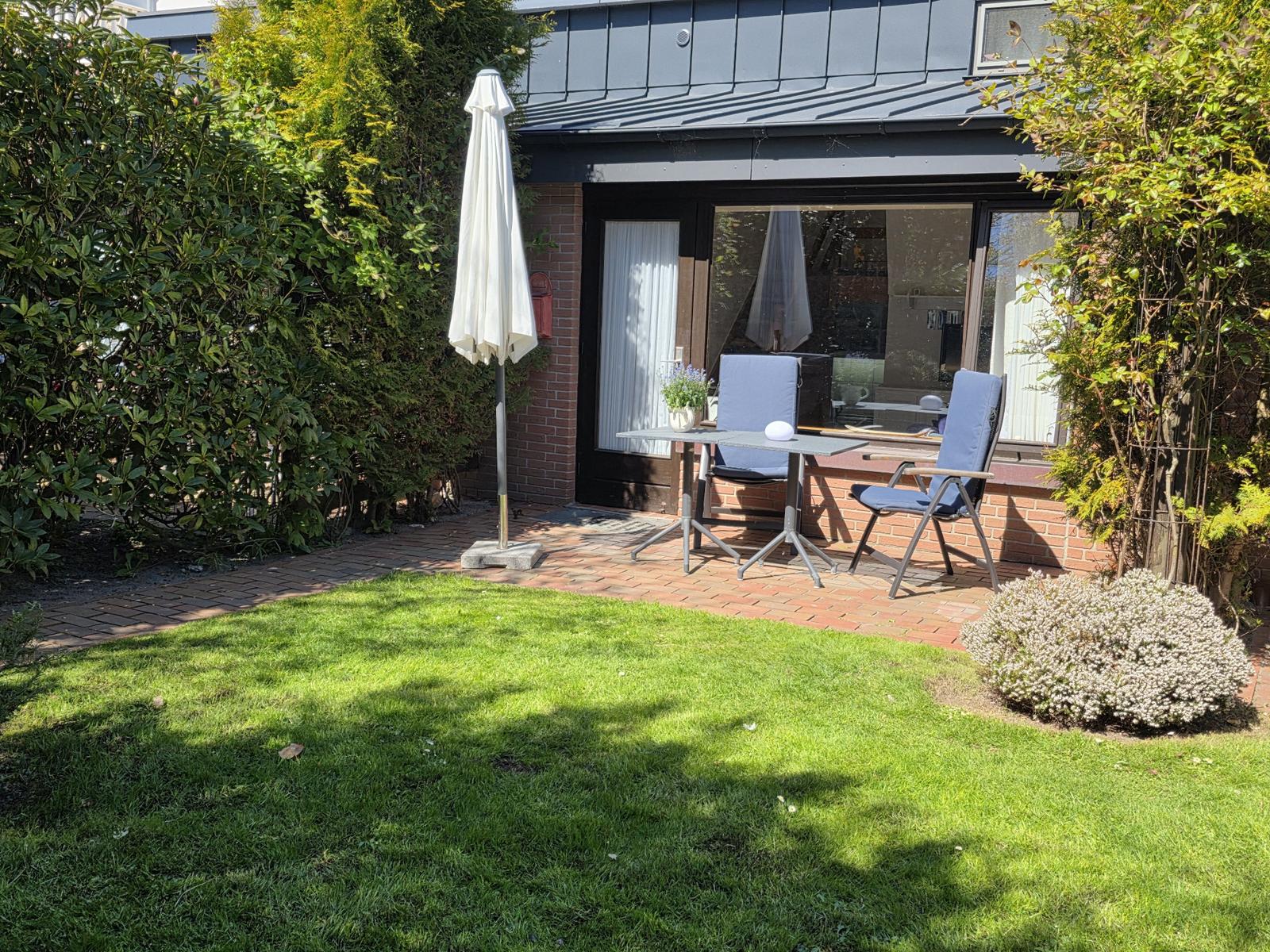 Terasse vor der Tür mit Blick in einen grünen, blühenden Garten