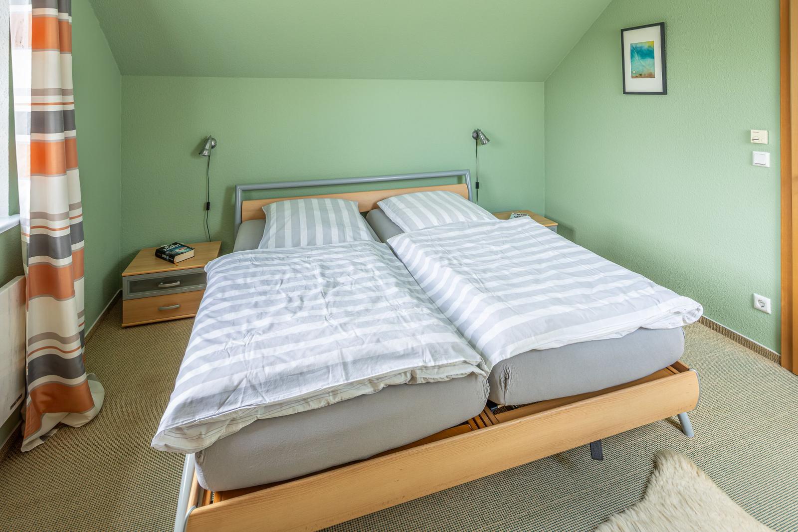 Schlafzimmer mit Doppelbett, grünen Wänden und Nachttischen mit Lampen.
