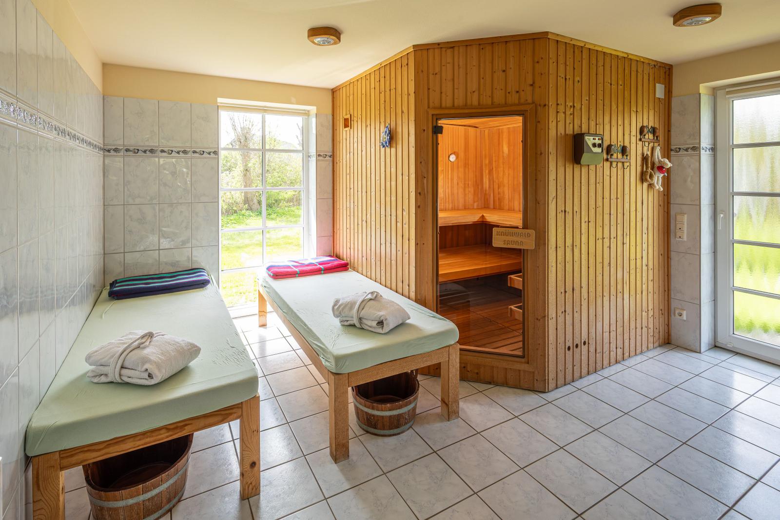 Sauna mit Holzverkleidung und zwei Liegen mit Handtüchern.