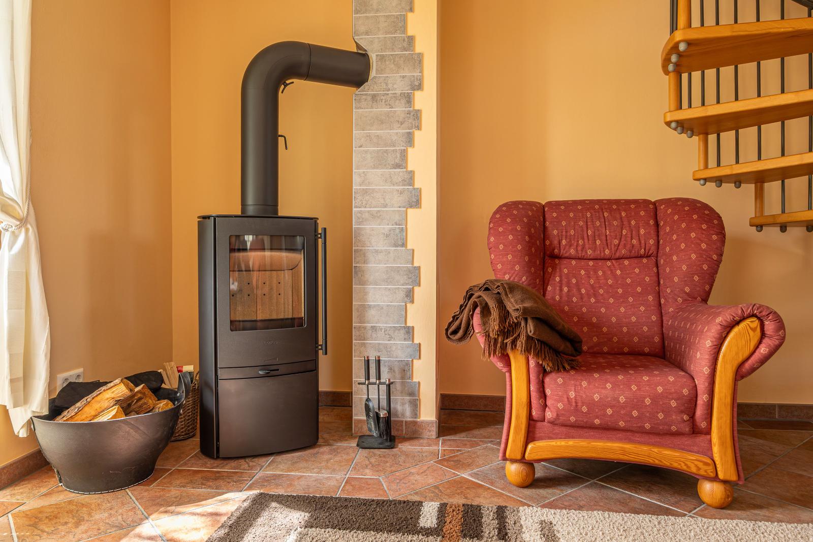 Kaminofen mit Holzstapel, rote Sessel und Holztreppe in Wohnzimmer