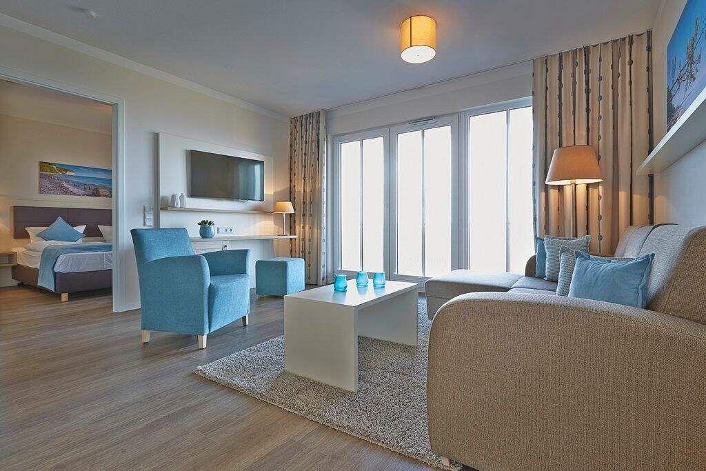 Wohnbereich mit Sofa, Sessel und TV. Durchgang zur Schlafzimmer.