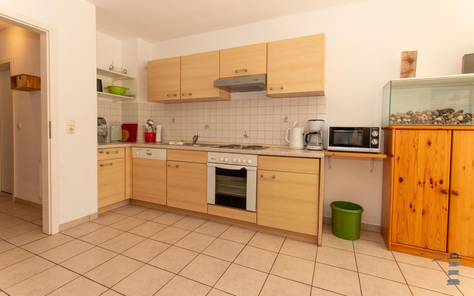 Küche mit Holzschränken, Herd, Mikrowelle und Aquarium.