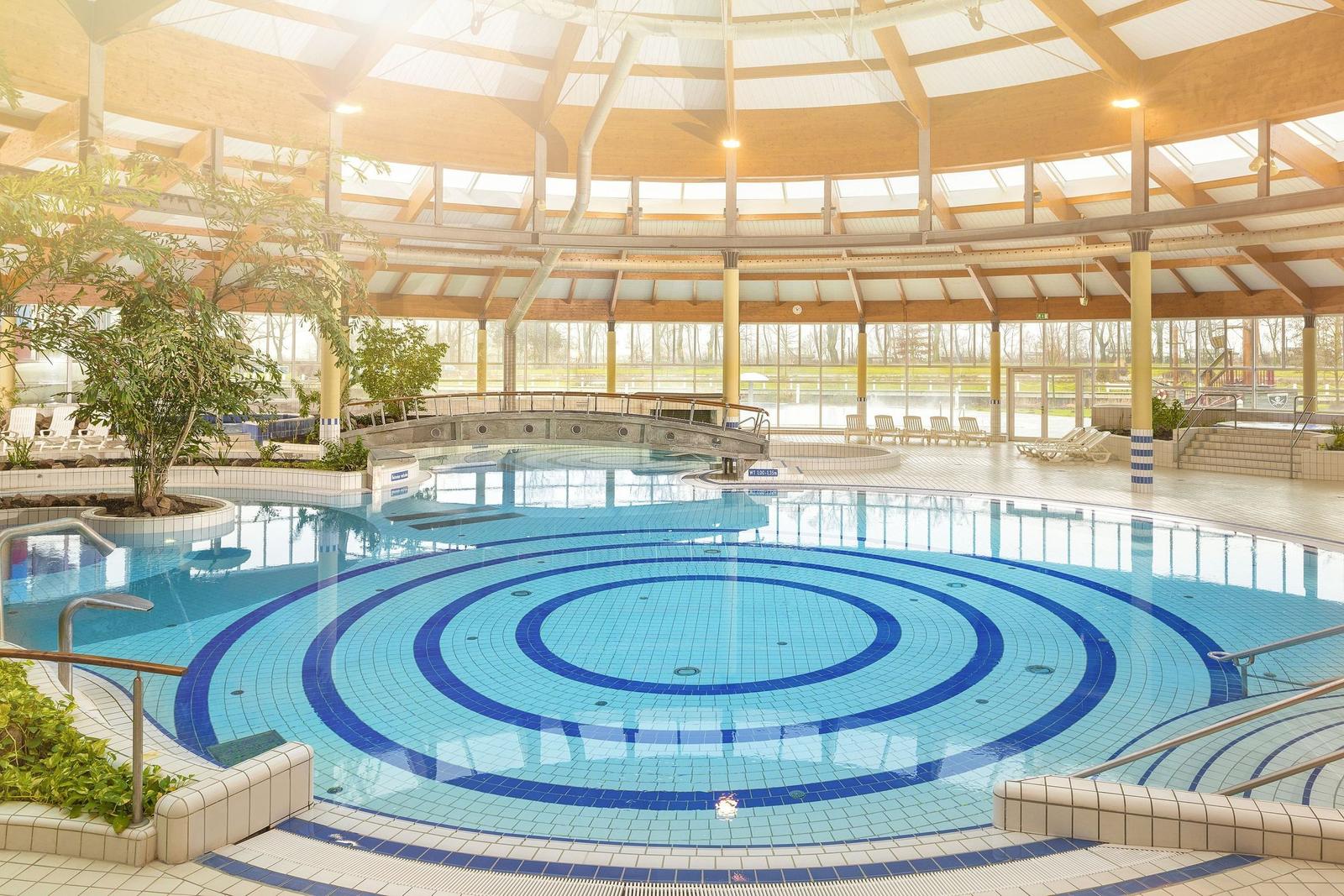 Großes Hallenbad mit blauen Mosaikmustern und Glasdach