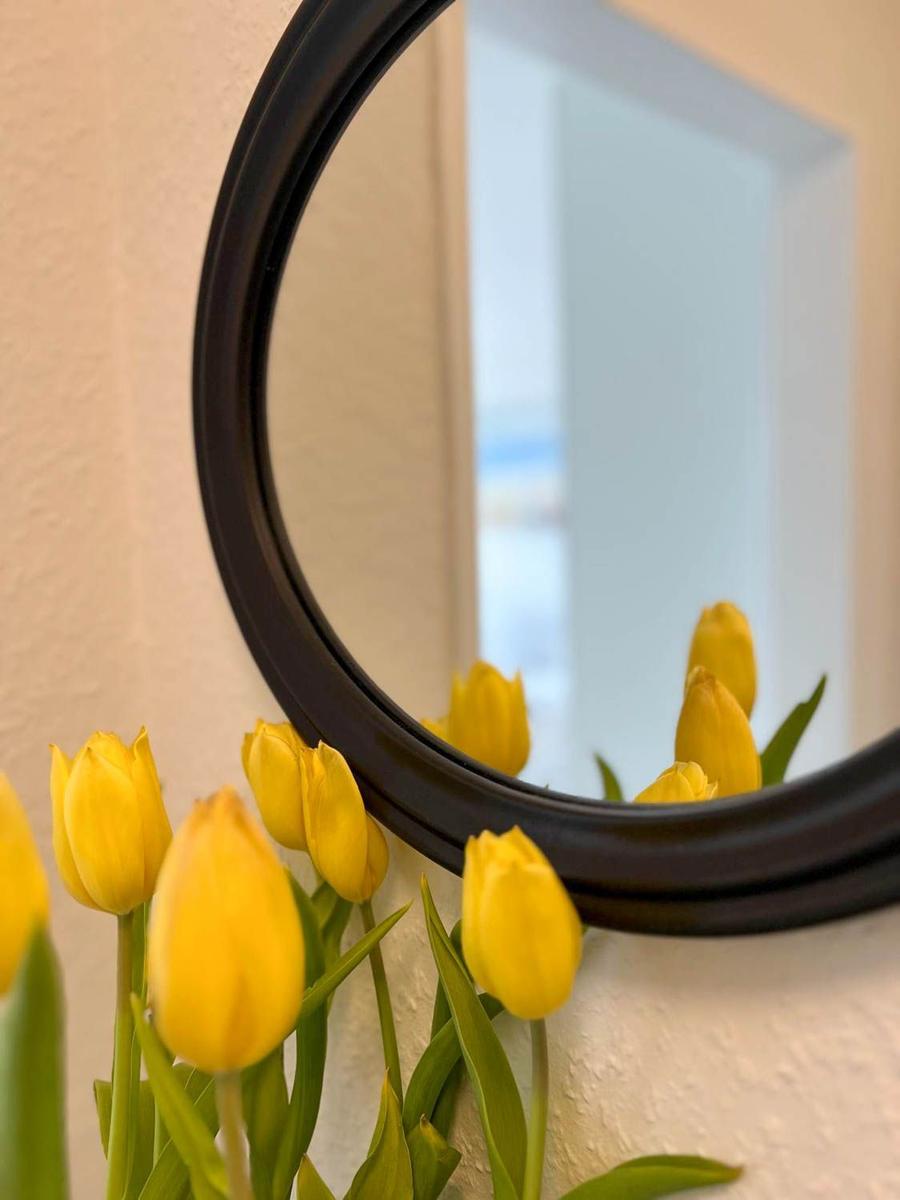 Runder Spiegel mit gelben Tulpen im Vordergrund