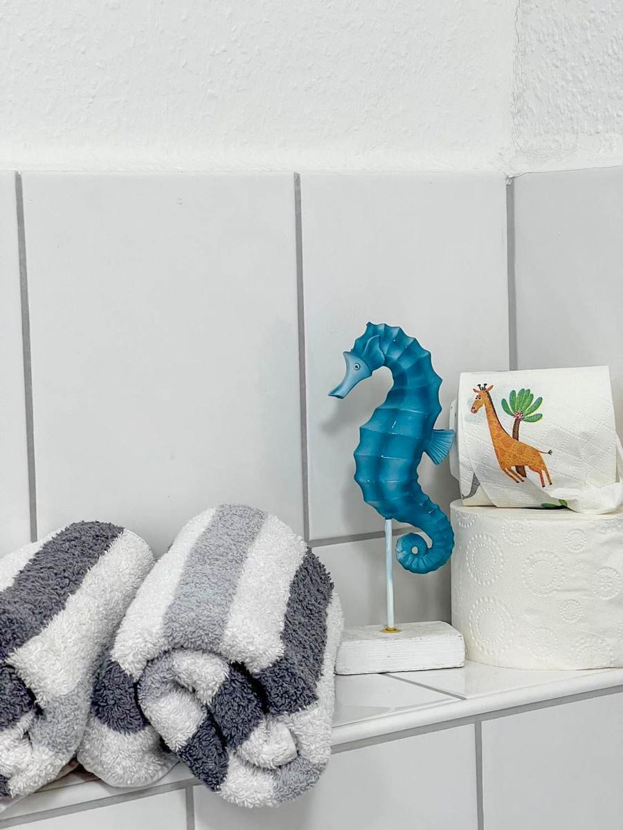 Badezimmer mit Handtuch, Seepferdchen-Dekoration und Toilettenpapierrolle.