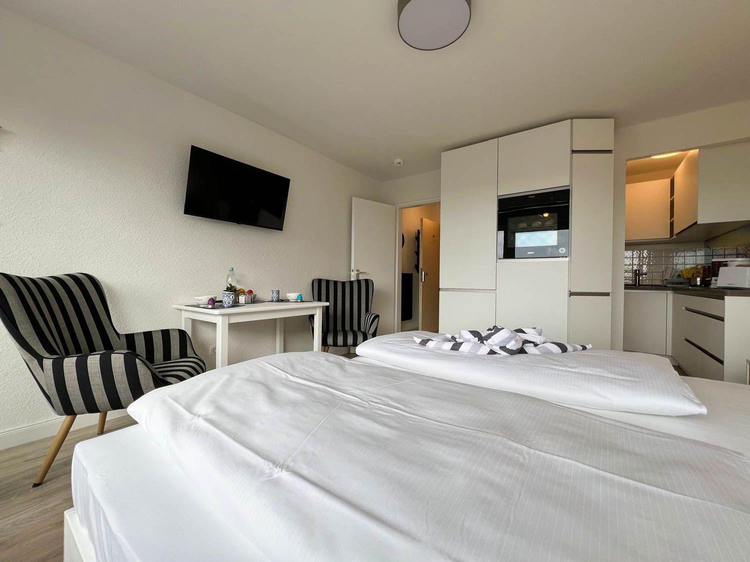Schlafzimmer mit Bett, TV und Küchenbereich.