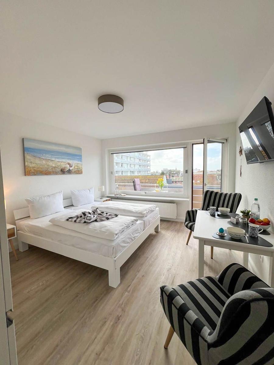 Schlafzimmer mit Doppelbett, Tisch mit Stühlen und Fenster zur Aussicht.