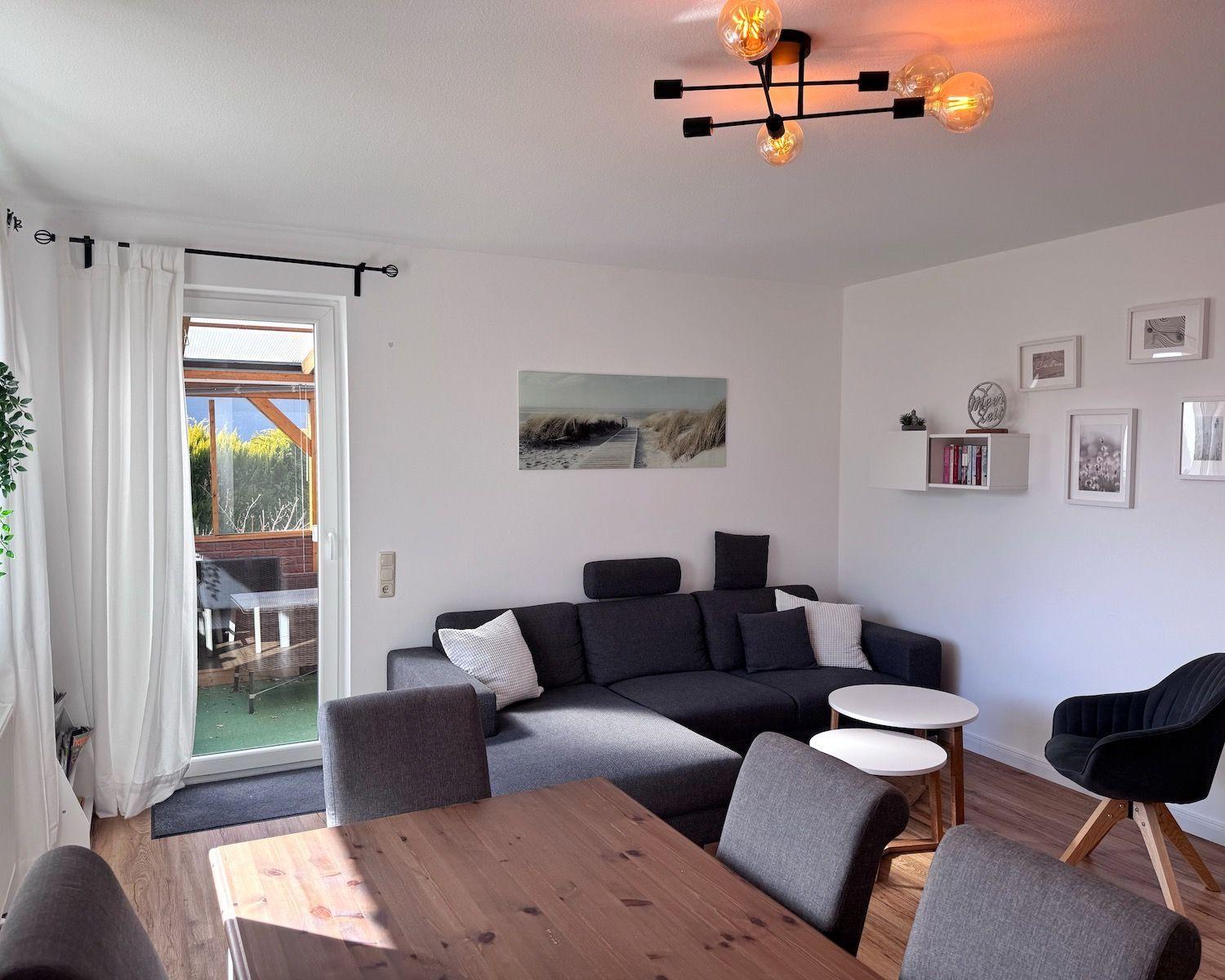 Wohnzimmer mit Sofa, Esstisch und Terrassentür.