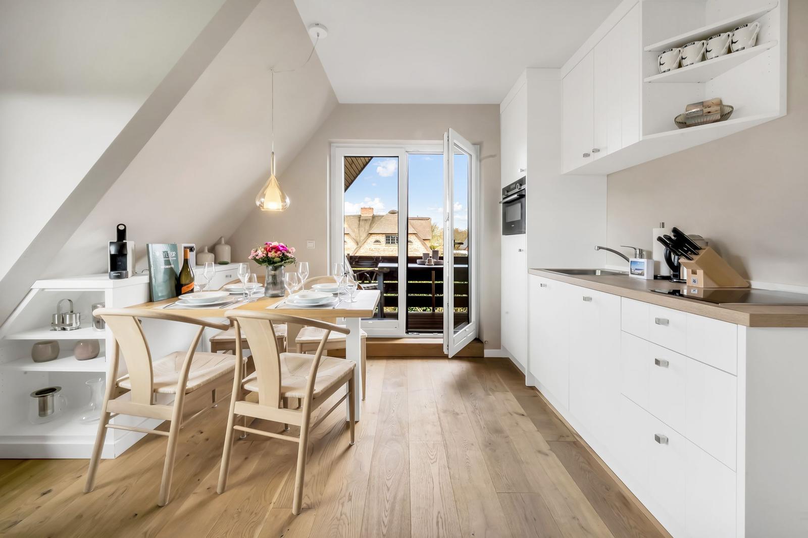 Kitchen and dining area with table, chairs, and balcony view.