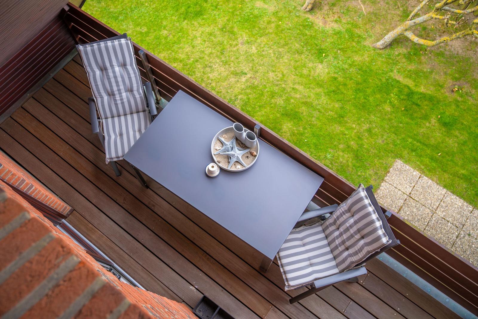 Terrace with table and two chairs, view of green lawn.