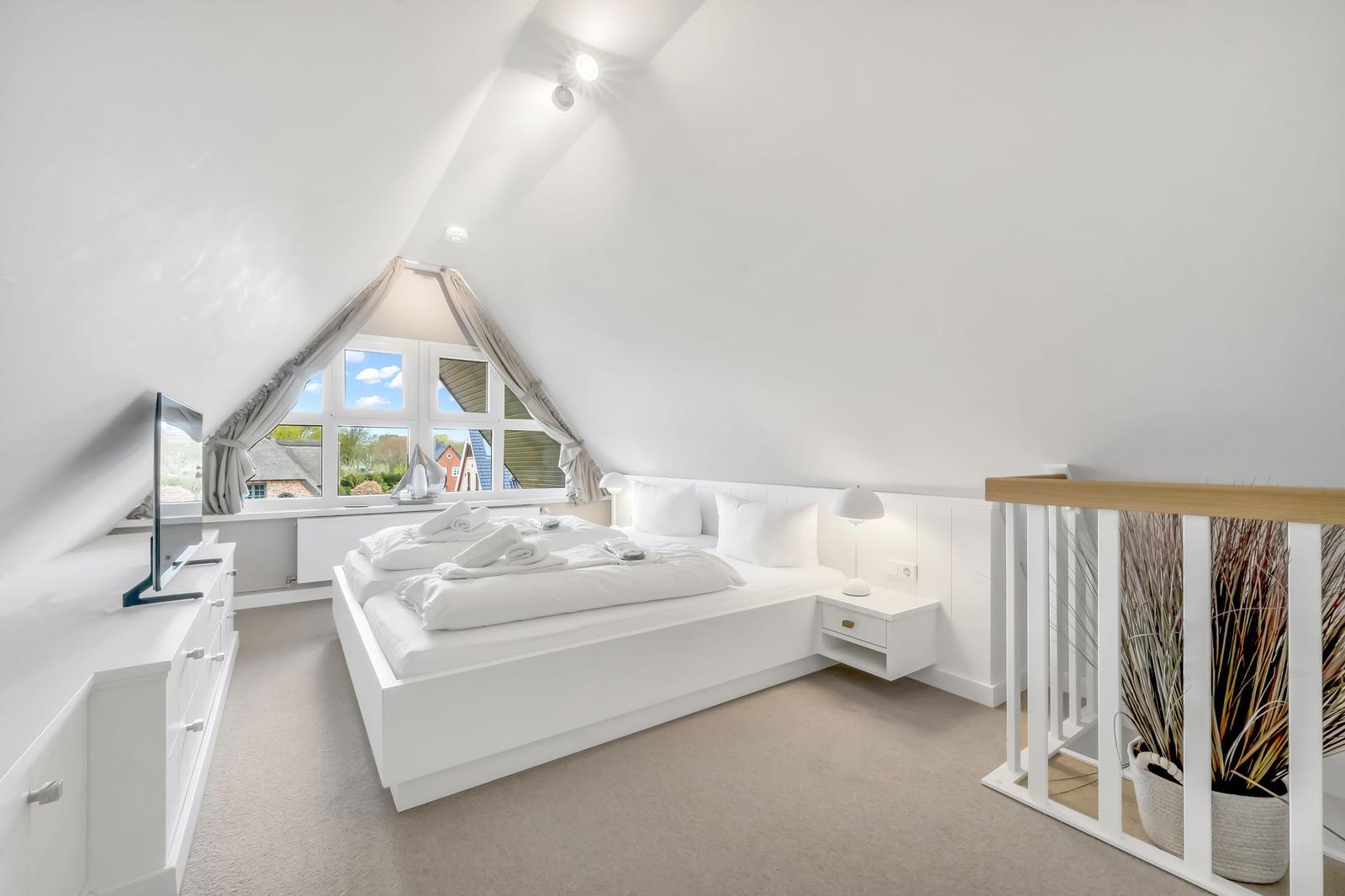 Bedroom with skylight, white bed, and TV cabinet.