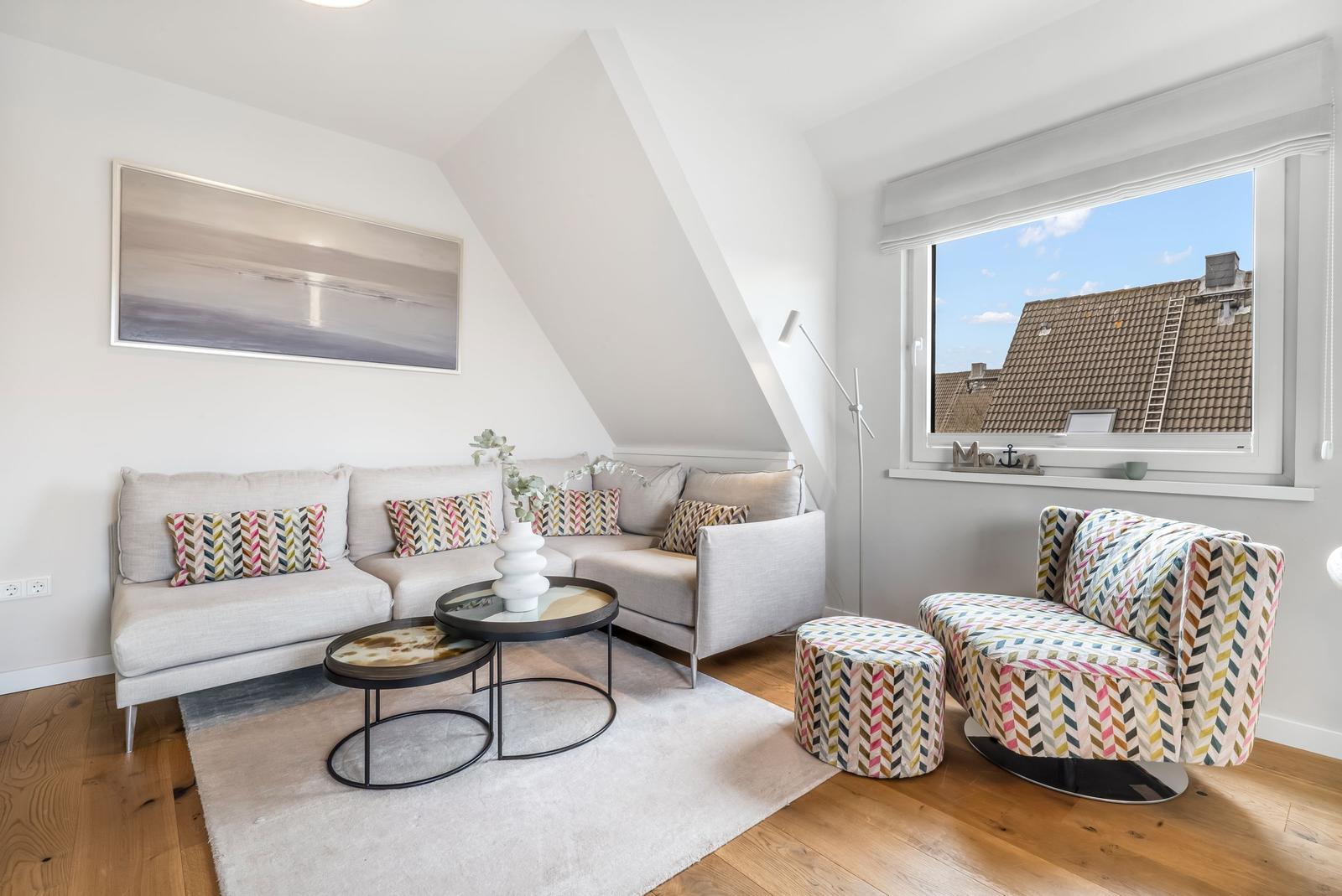 Living room with sofa, armchair, and table under sloped ceiling