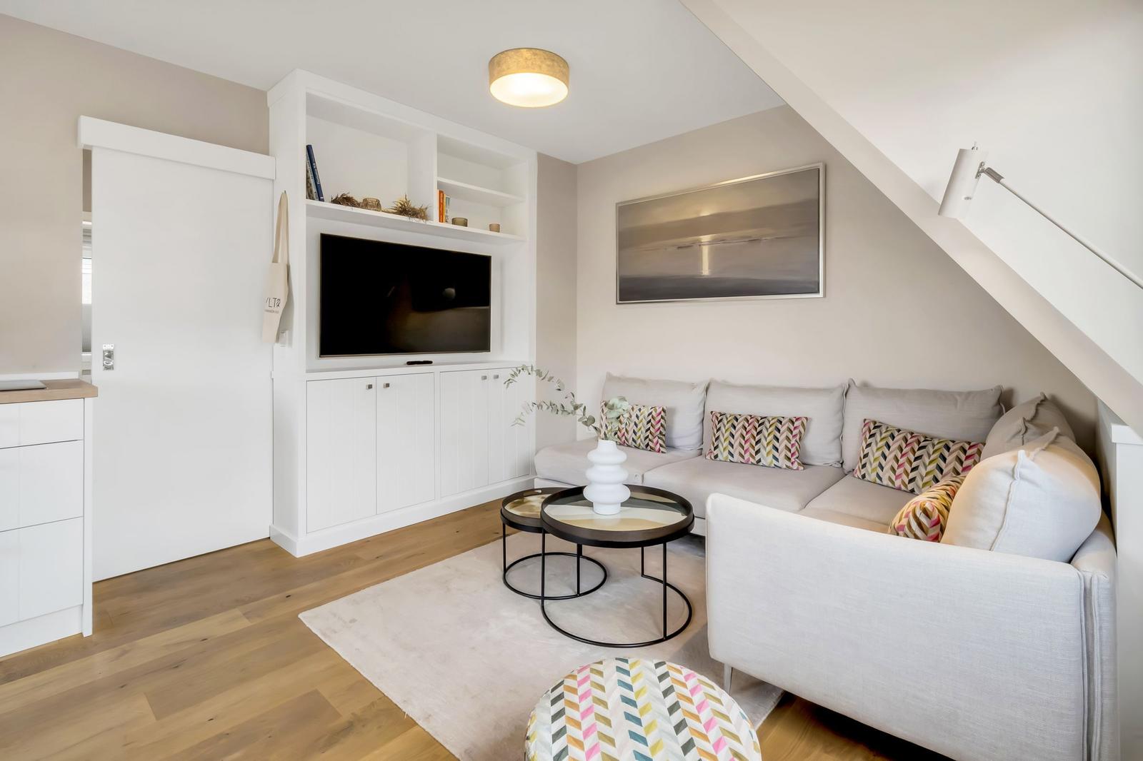 Living room with sofa, TV, and coffee table under sloped ceiling.