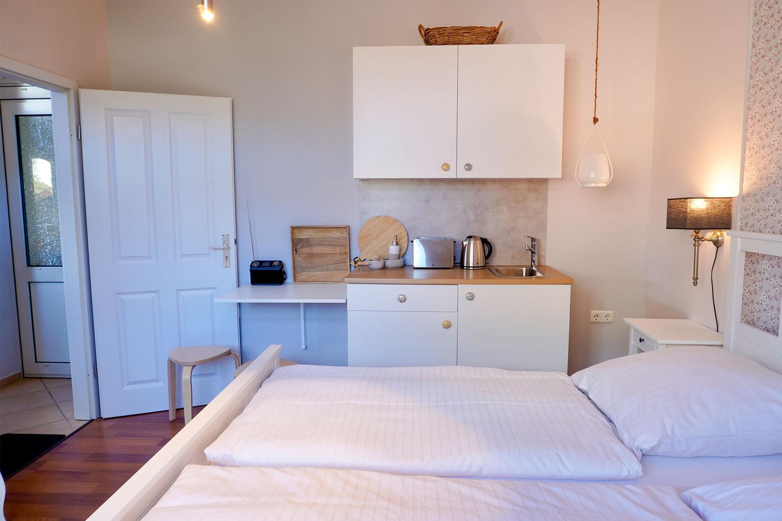 Schlafzimmer mit kleiner Küchenzeile und Schreibtisch.