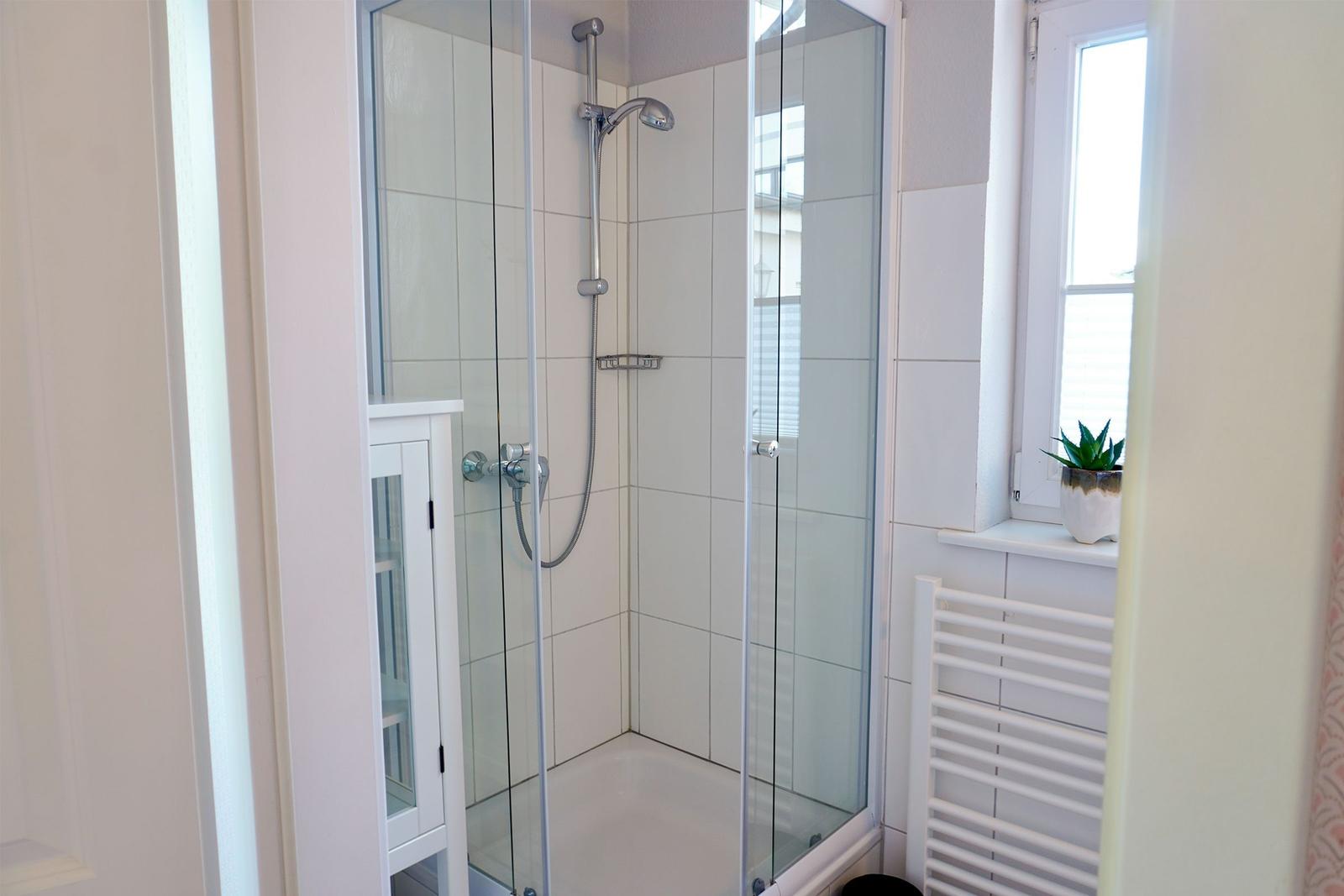 Dusche mit Glaswand, Fenster und Heizkörper