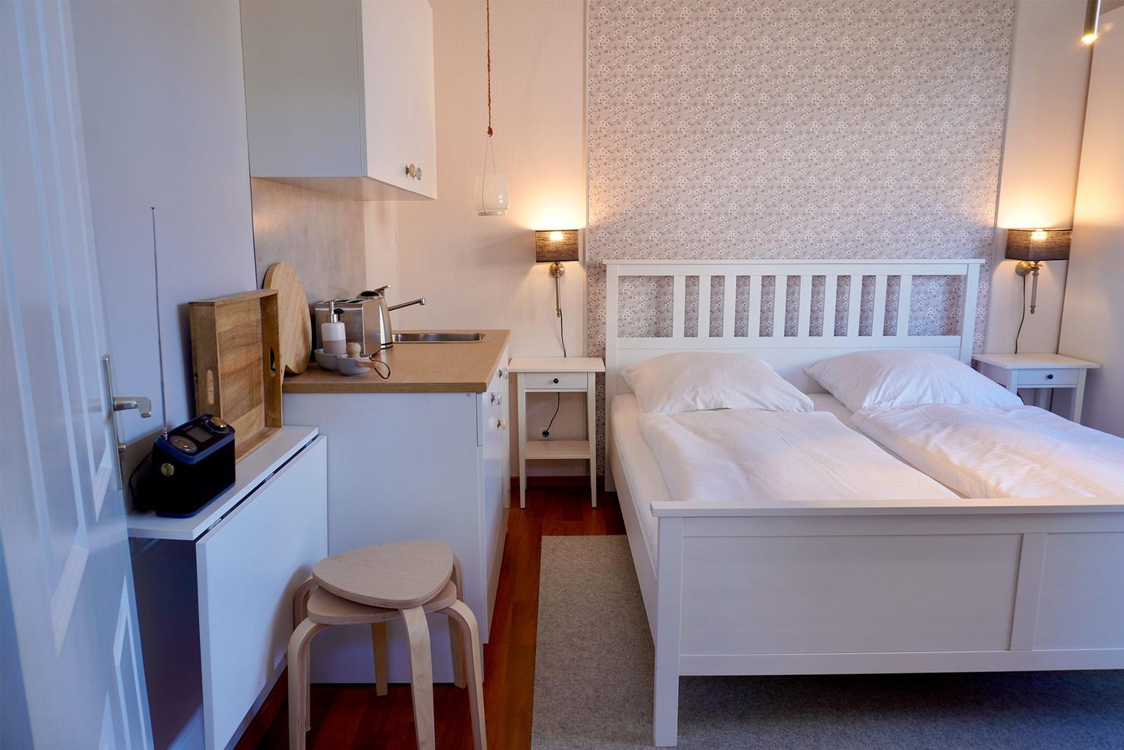 Ein Schlafzimmer mit Doppelbett, zwei Nachttischen und einer Küchenzeile.