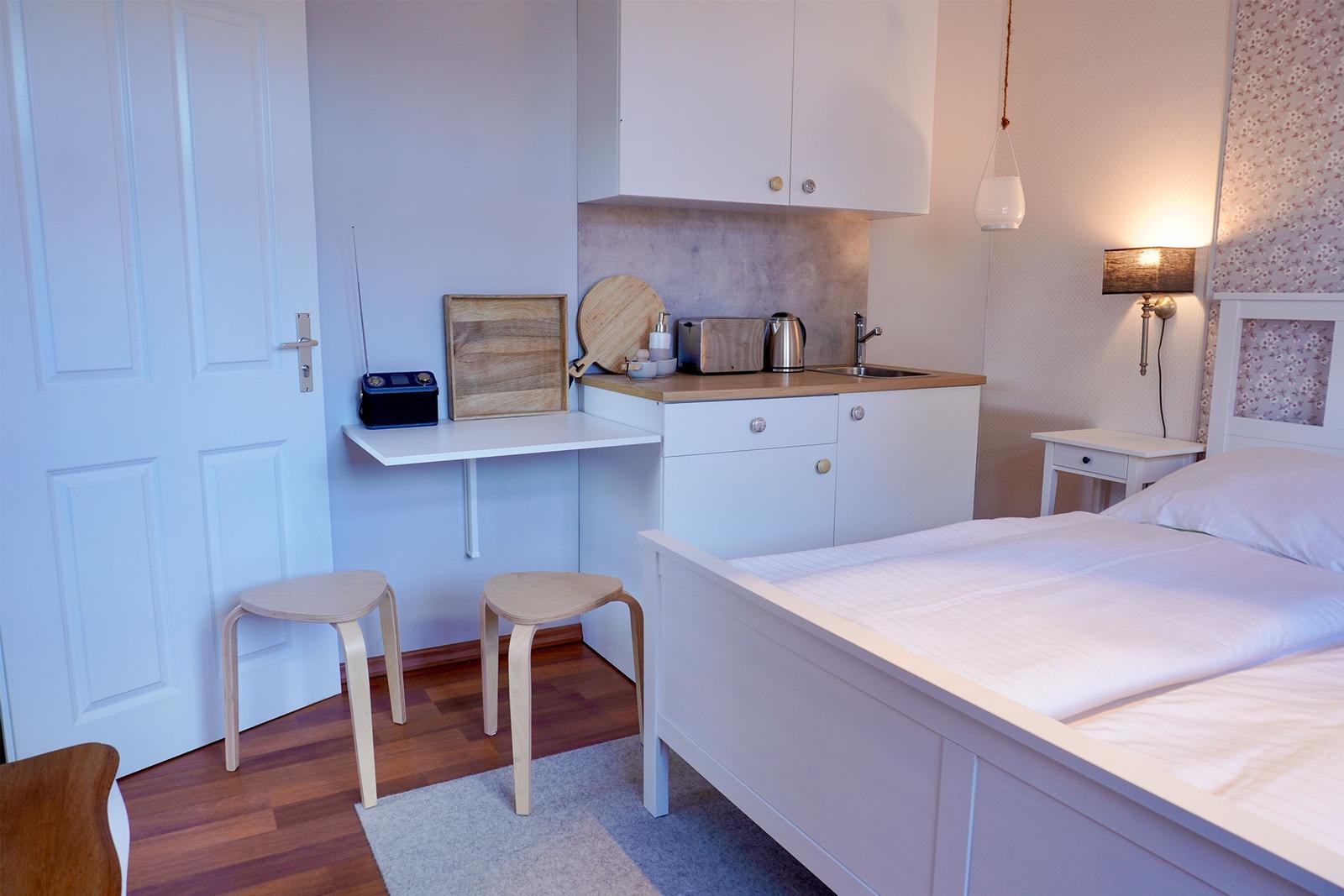 Ein Schlafzimmer mit Bett, Küchenzeile und Schreibtisch.