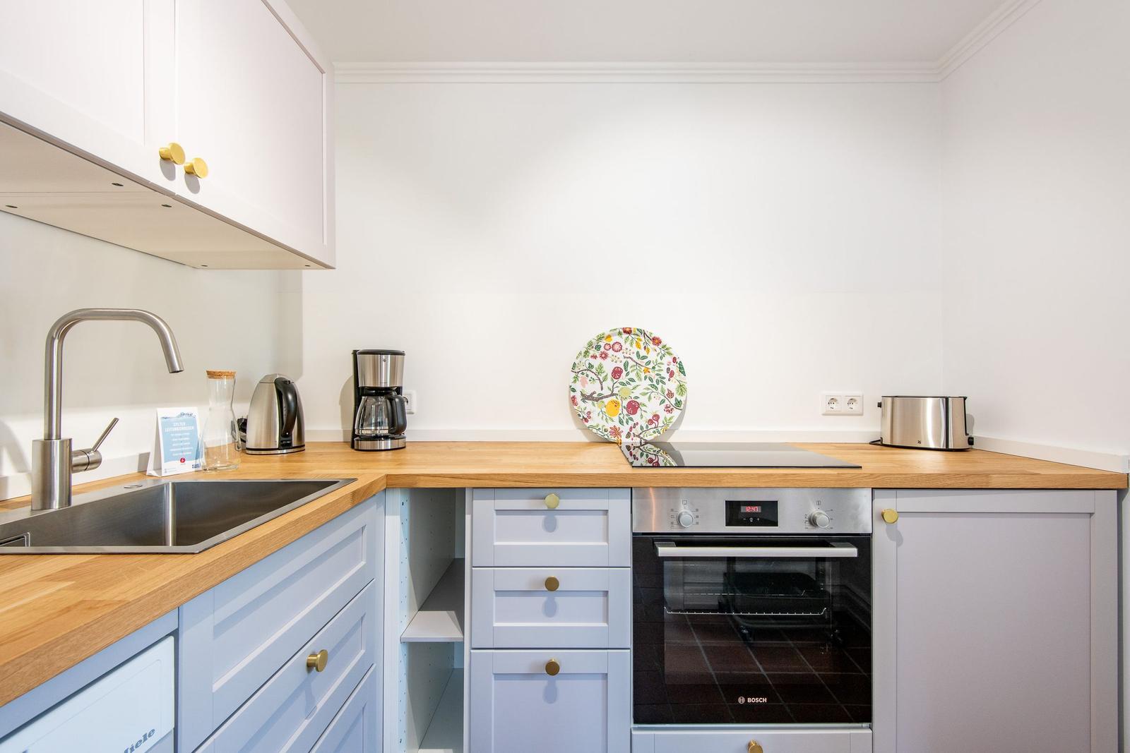Kitchen with wooden countertop, stainless steel sink, and Bosch cooktop.
