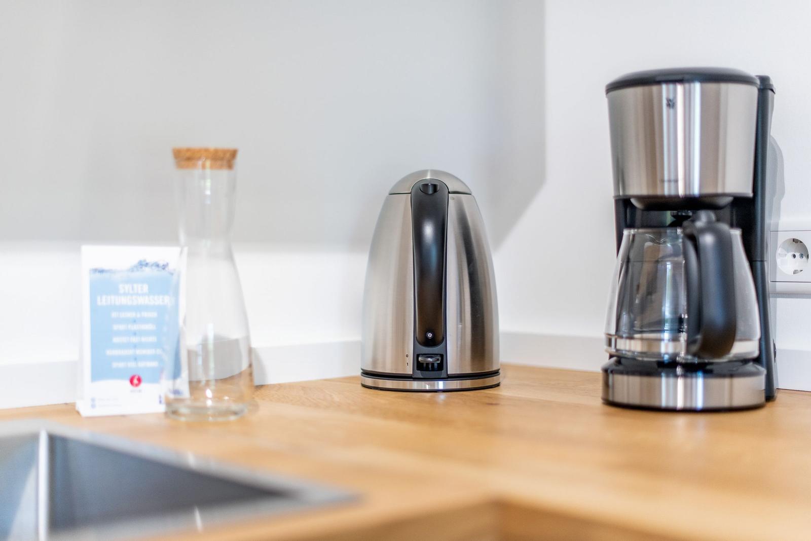 Kitchen counter with coffee maker, kettle, and water glass