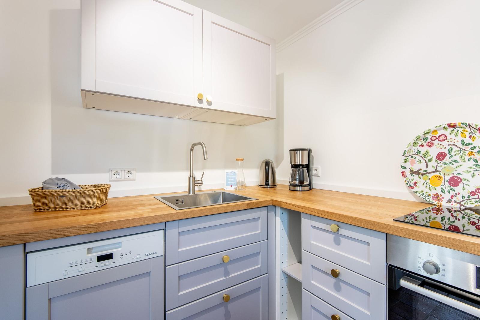 Kitchen with wooden countertops, white cabinets, and stainless steel sink.