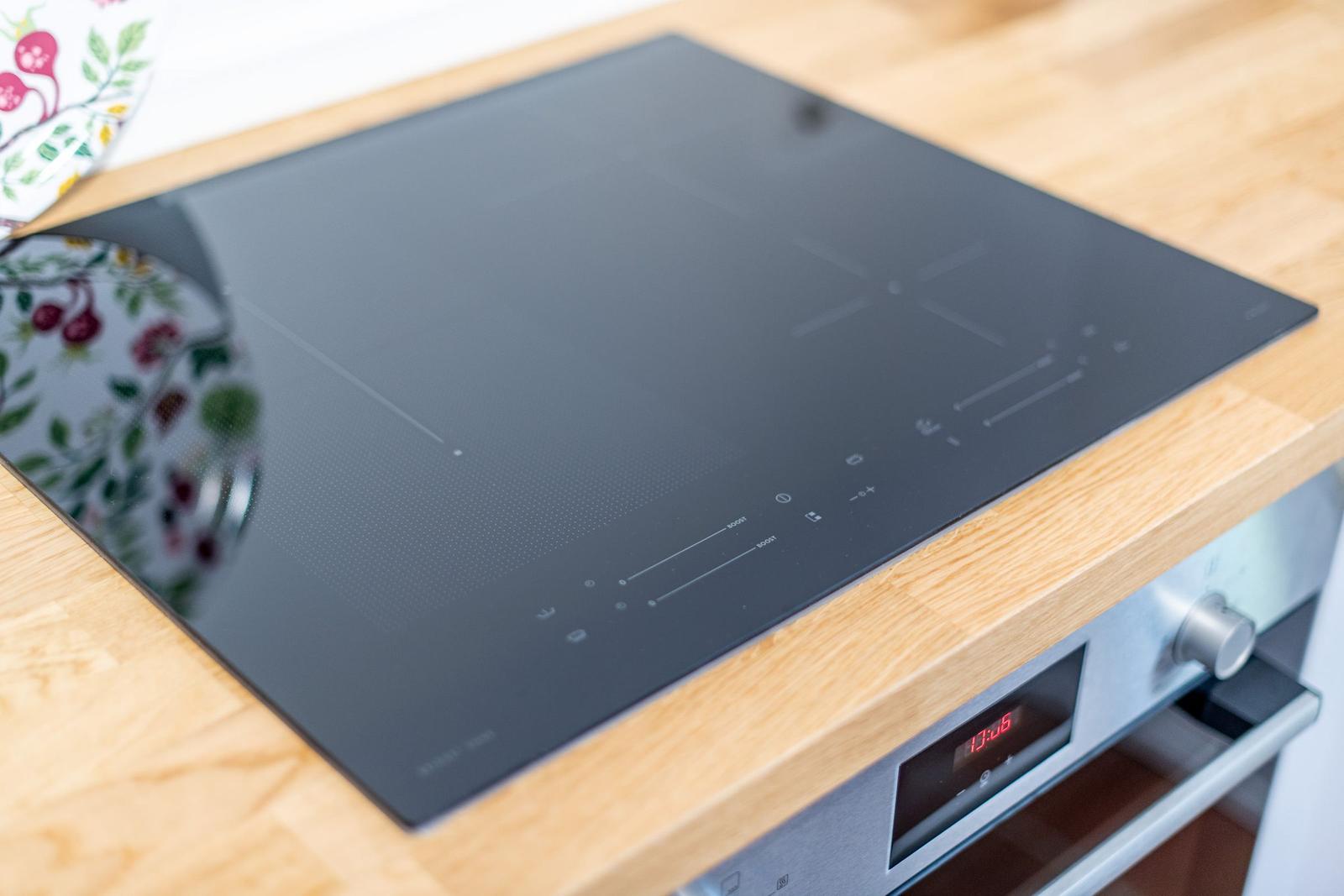 Induction cooktop on wooden surface with digital display and control elements.