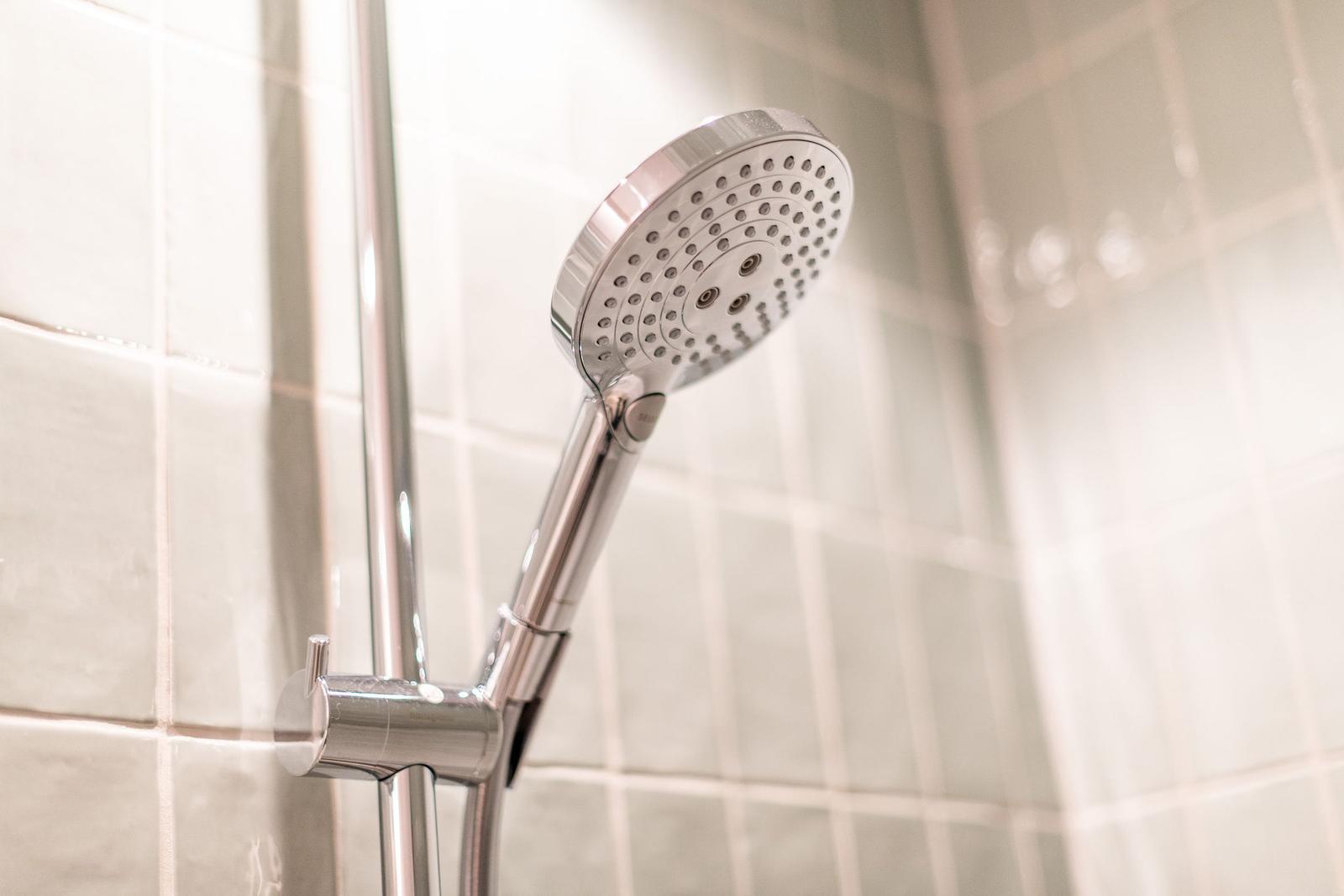 Shower head with handheld shower on tiled wall