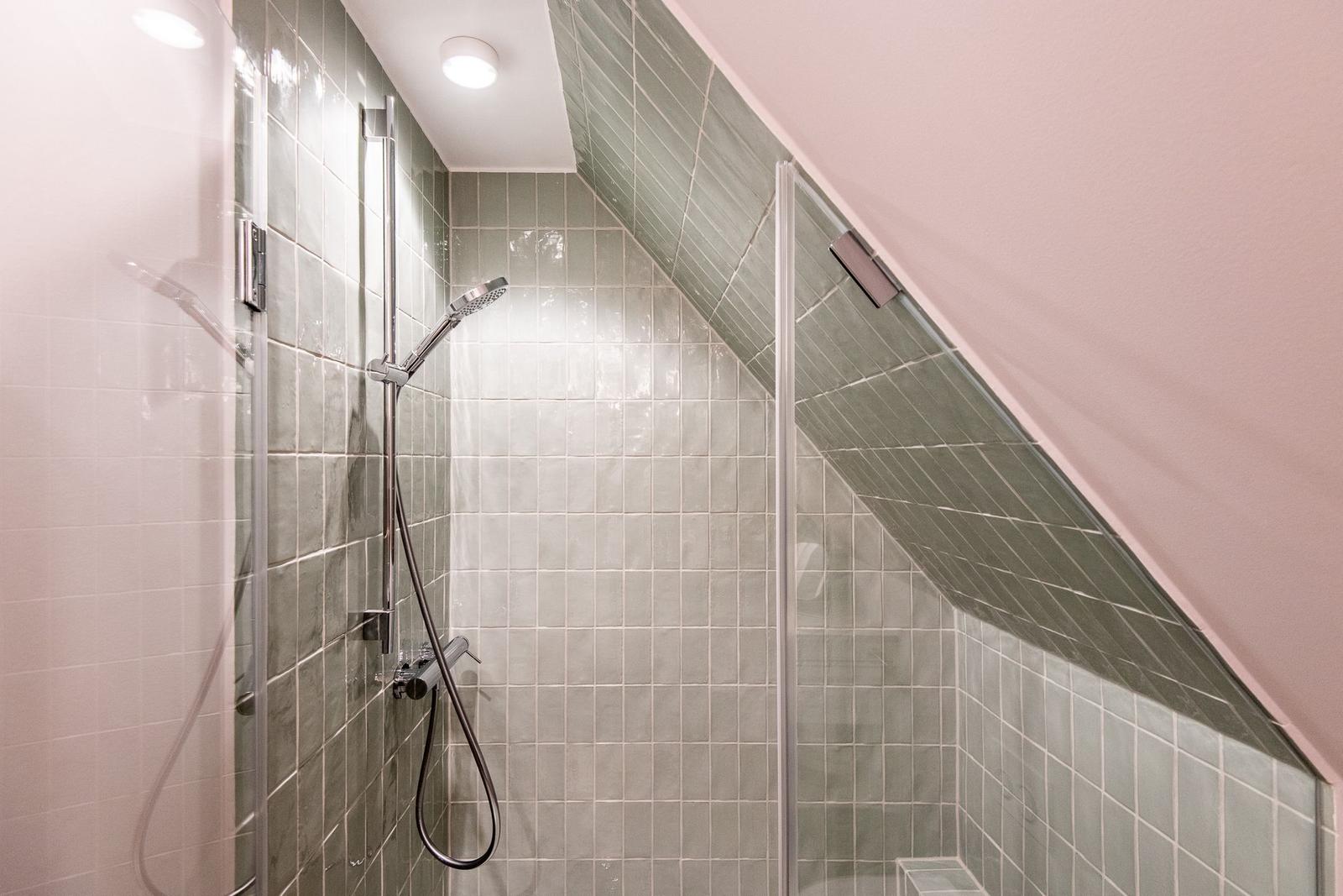 Shower with glass enclosure and handheld showerhead