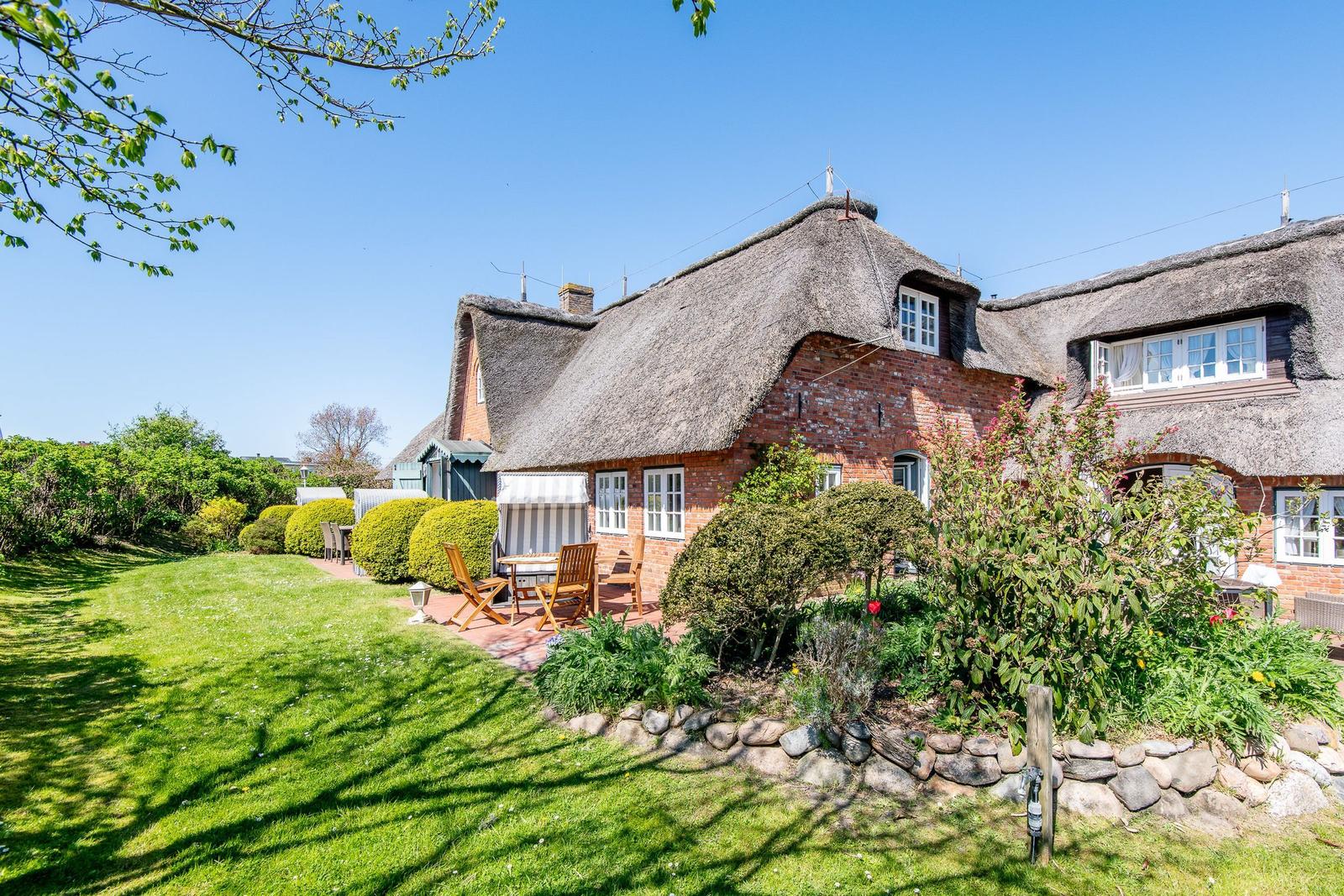 Red brick building with thatched roof and garden area with seating.