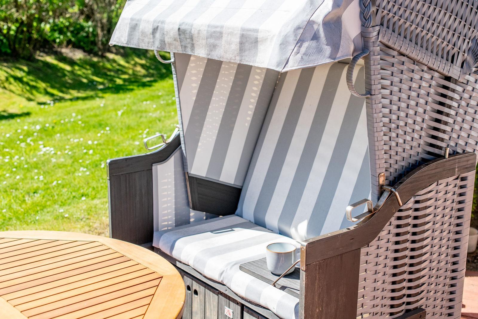 Hanging chair with striped cover and sunshade in the garden