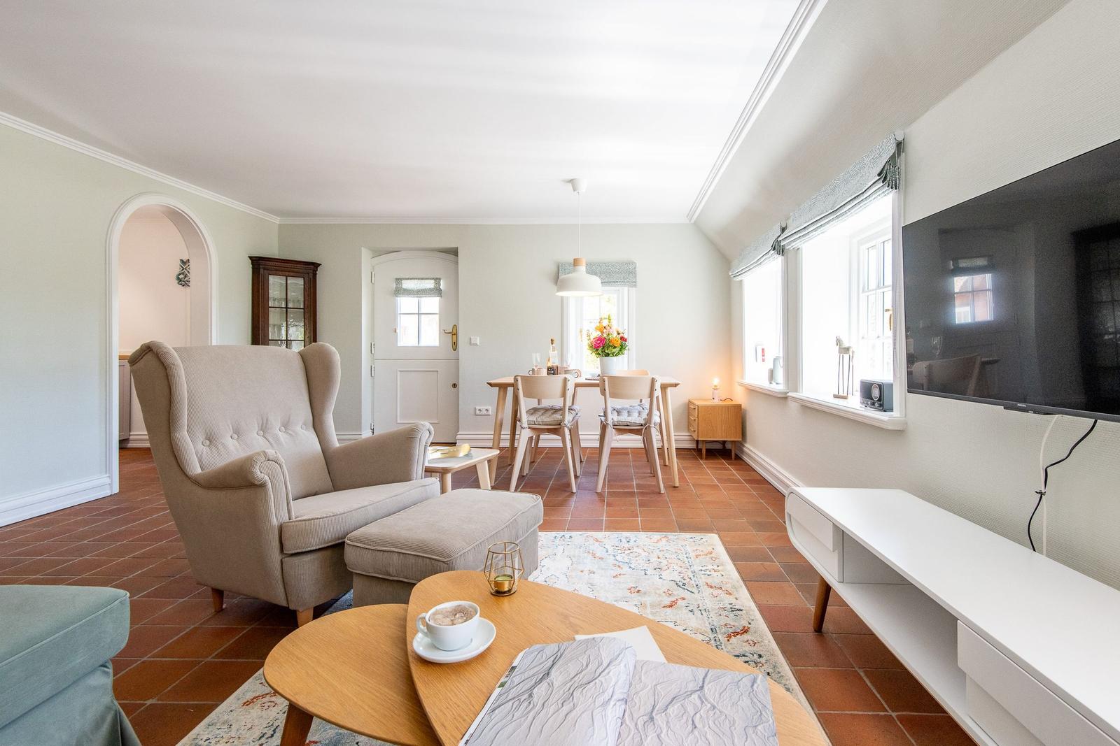 Living and dining area with armchair, table, and TV.