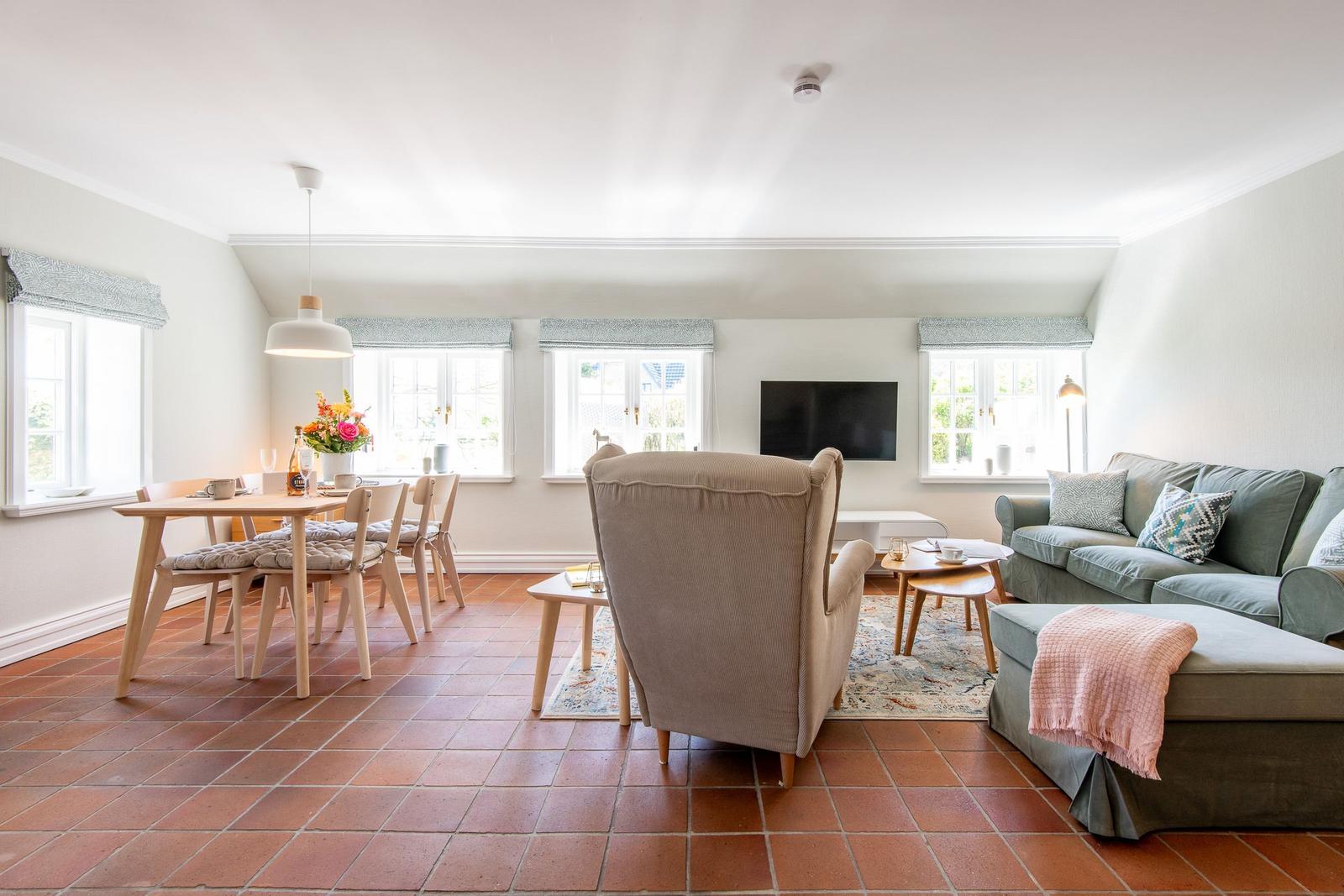Living and dining area with sofa, armchair, and dining set on terracotta floor.