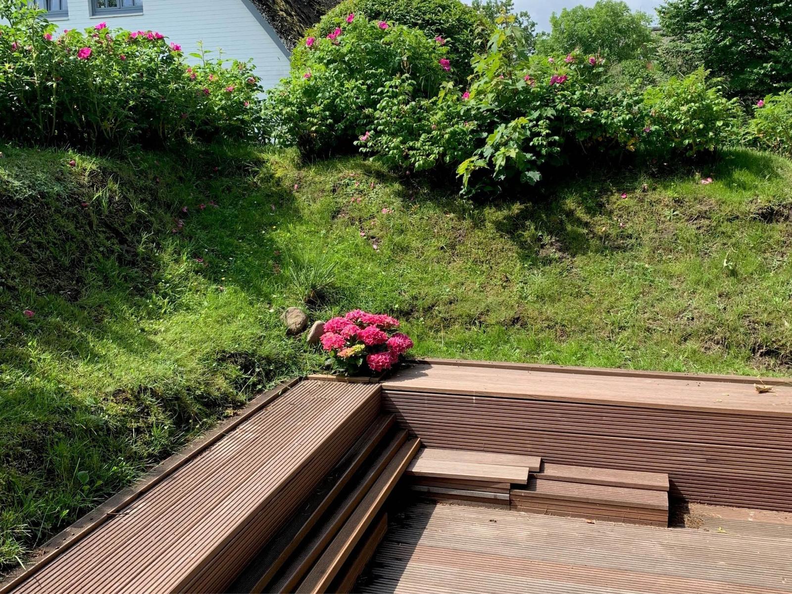 Holzterrasse mit Stufen und Blumenbeete im Garten