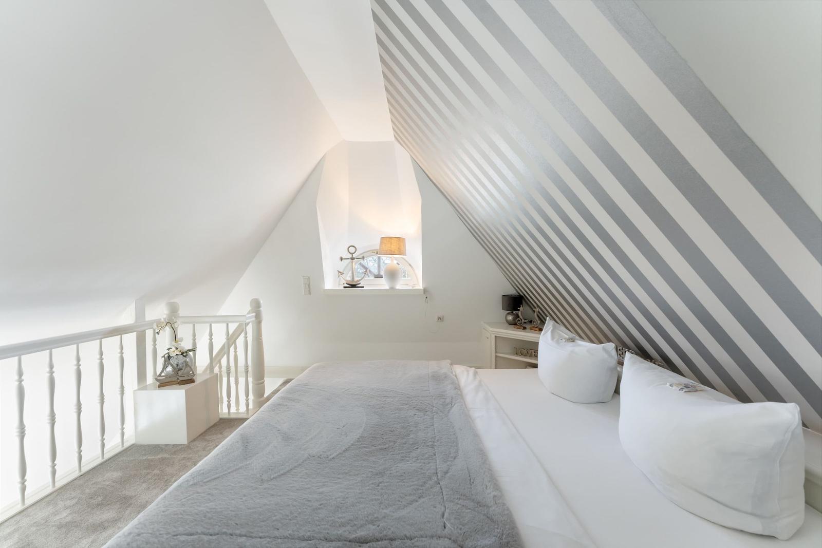 Schlafzimmer mit Dachschrägen, Bett und Fenster