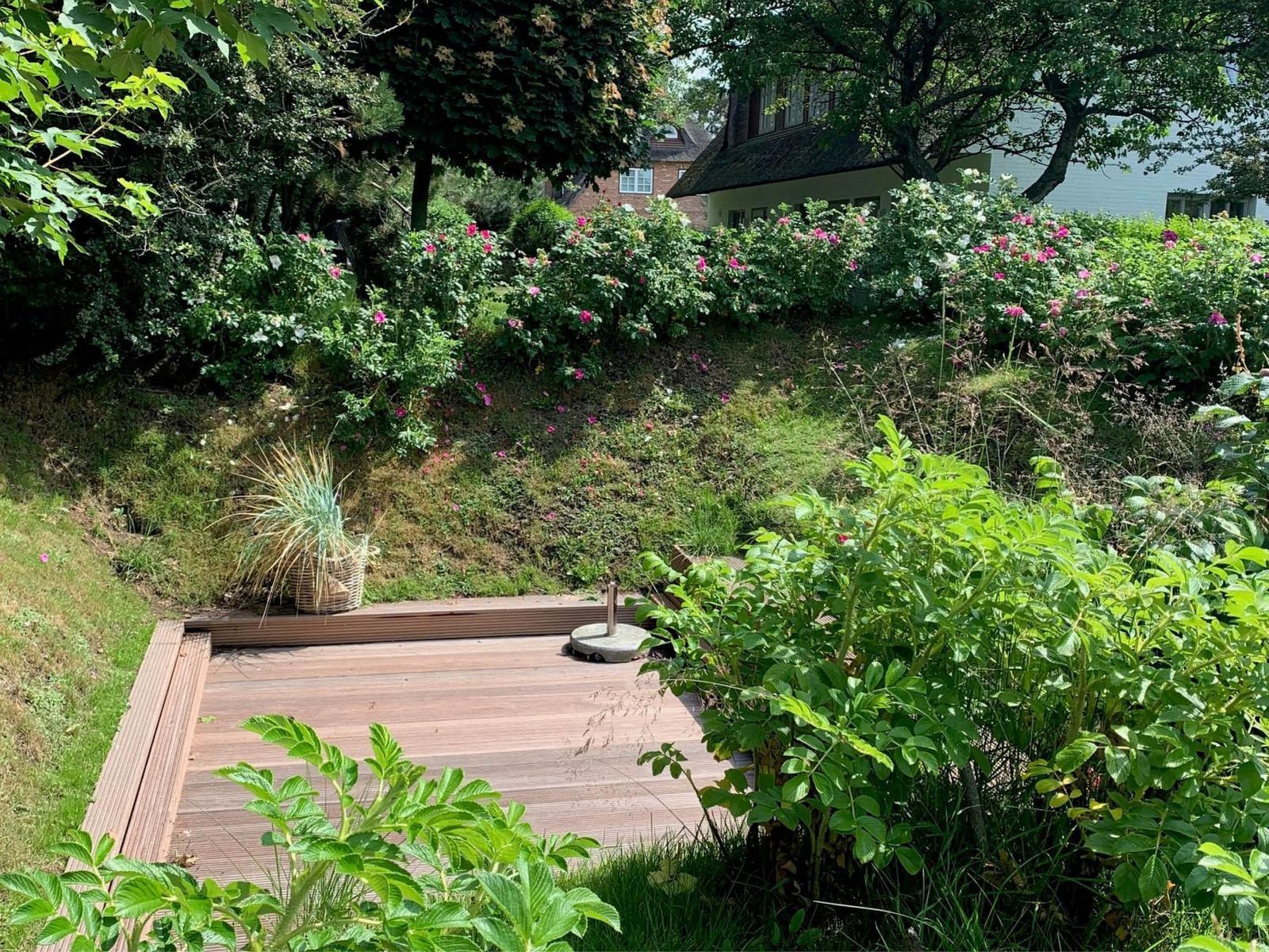 Holzterrasse mit Garten, Rosenbeete und Blick auf Haus