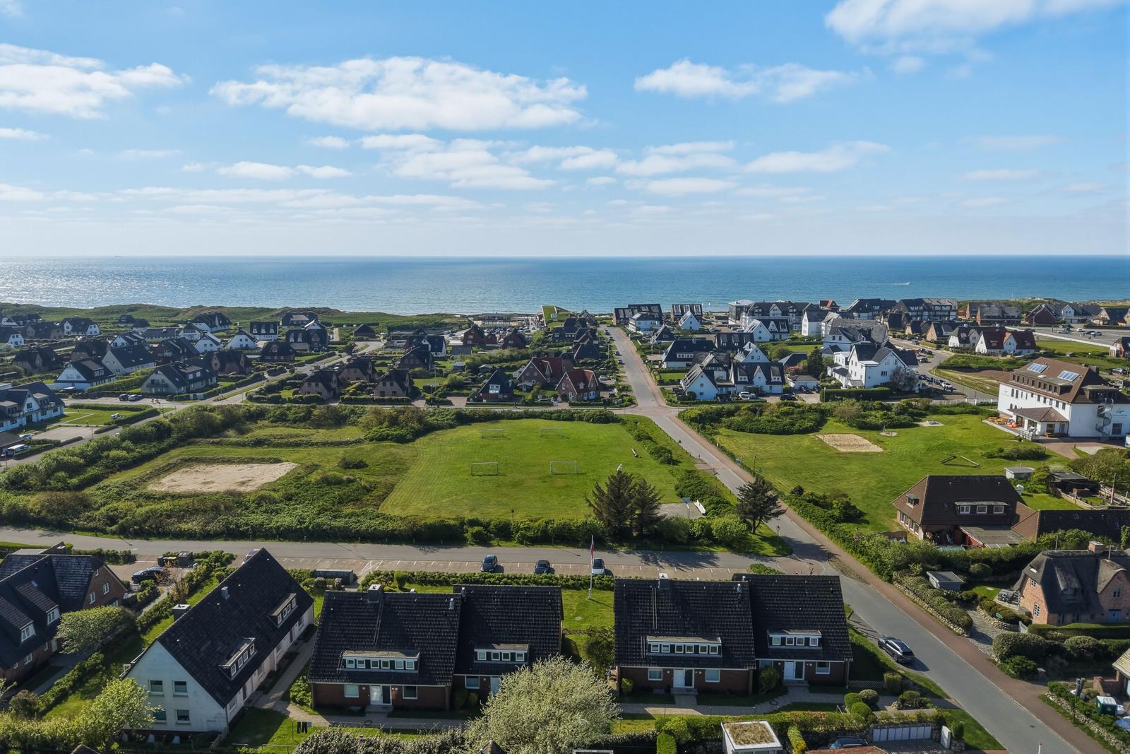 Übersicht über Stranddorf mit Häusern und grünem Feld nahe Meer.