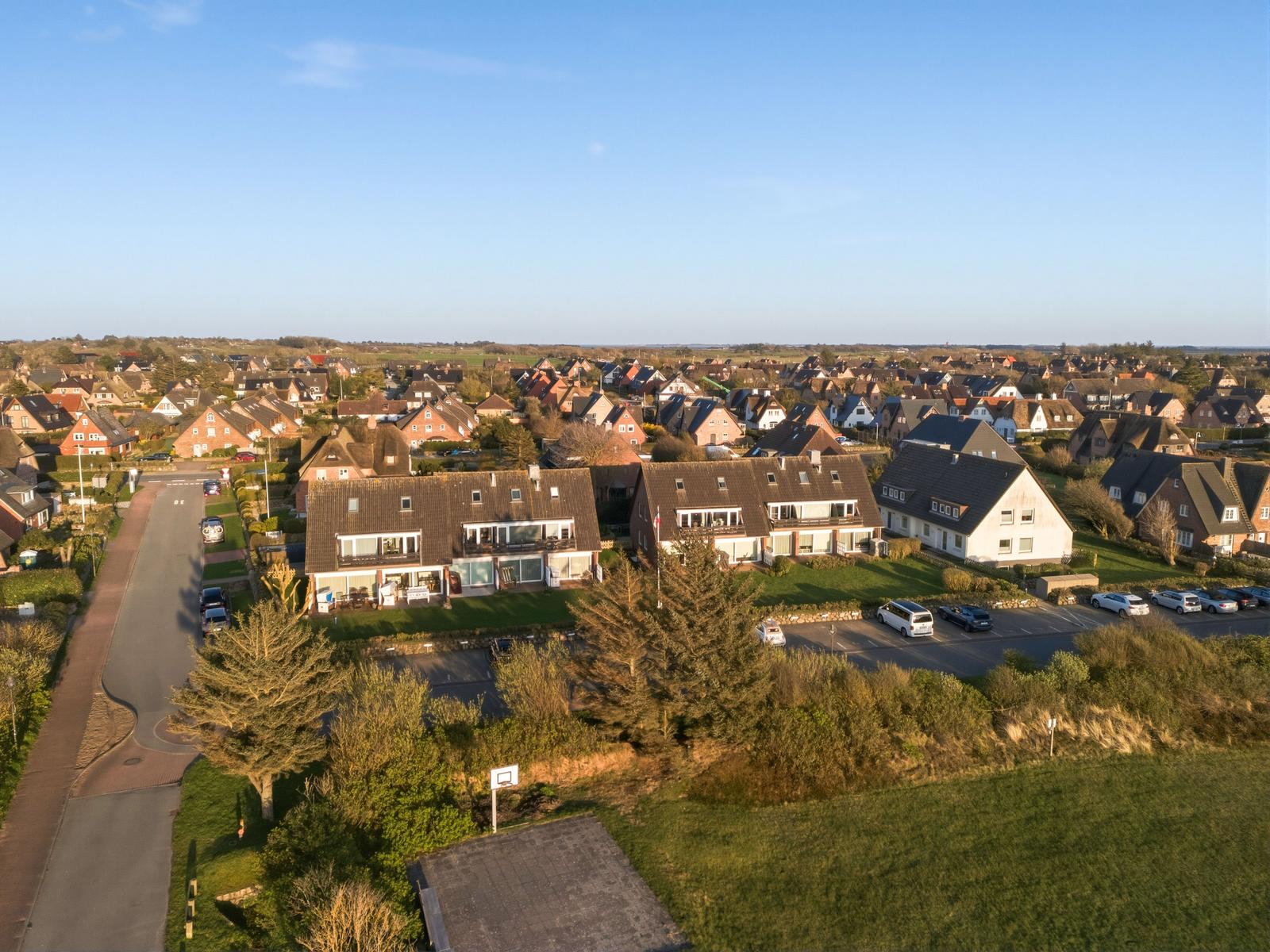 Aussicht auf Wohngebiet mit mehreren Häusern und grünen Flächen unter blauem Himmel.
