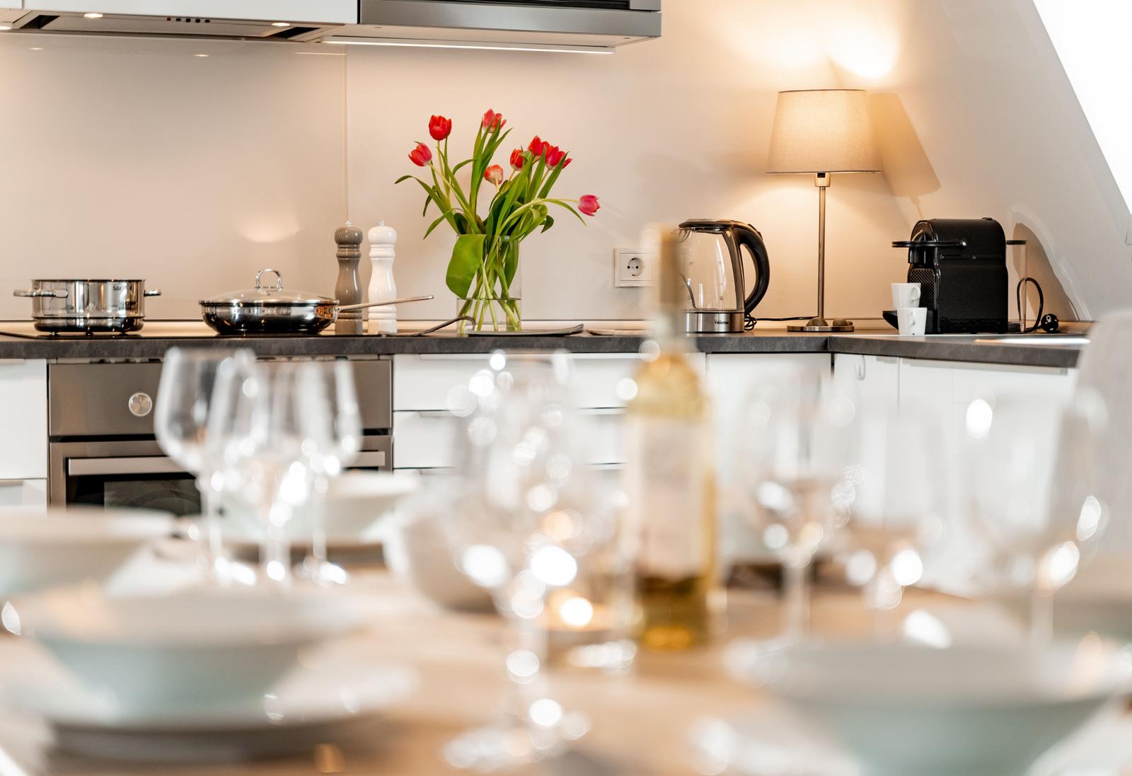 Küche mit Tisch, Gläsern und roten Tulpen auf der Arbeitsfläche.